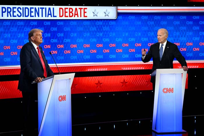 Donald Trump and Joe Biden stand at podiums during a CNN-hosted presidential debate, engaging in discussion. The background displays the text &quot;Presidential Debate.&quot;