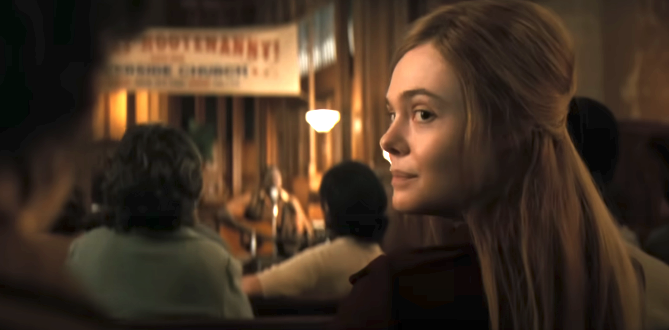Elizabeth Olsen in a scene from a movie, sits in an audience, turning to look at the camera. A banner in the background reads "Employment" and "Success Program."