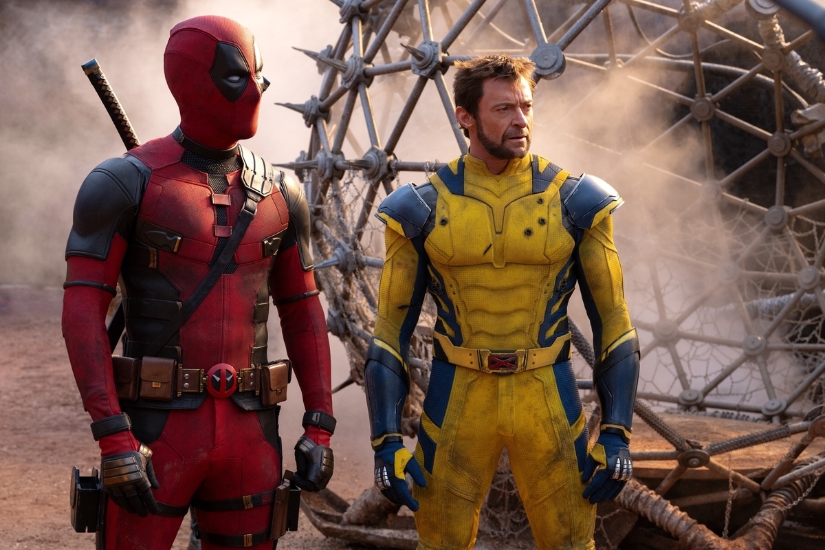 Ryan Reynolds as Deadpool and Hugh Jackman as Wolverine in costume standing outside amidst a smoky background