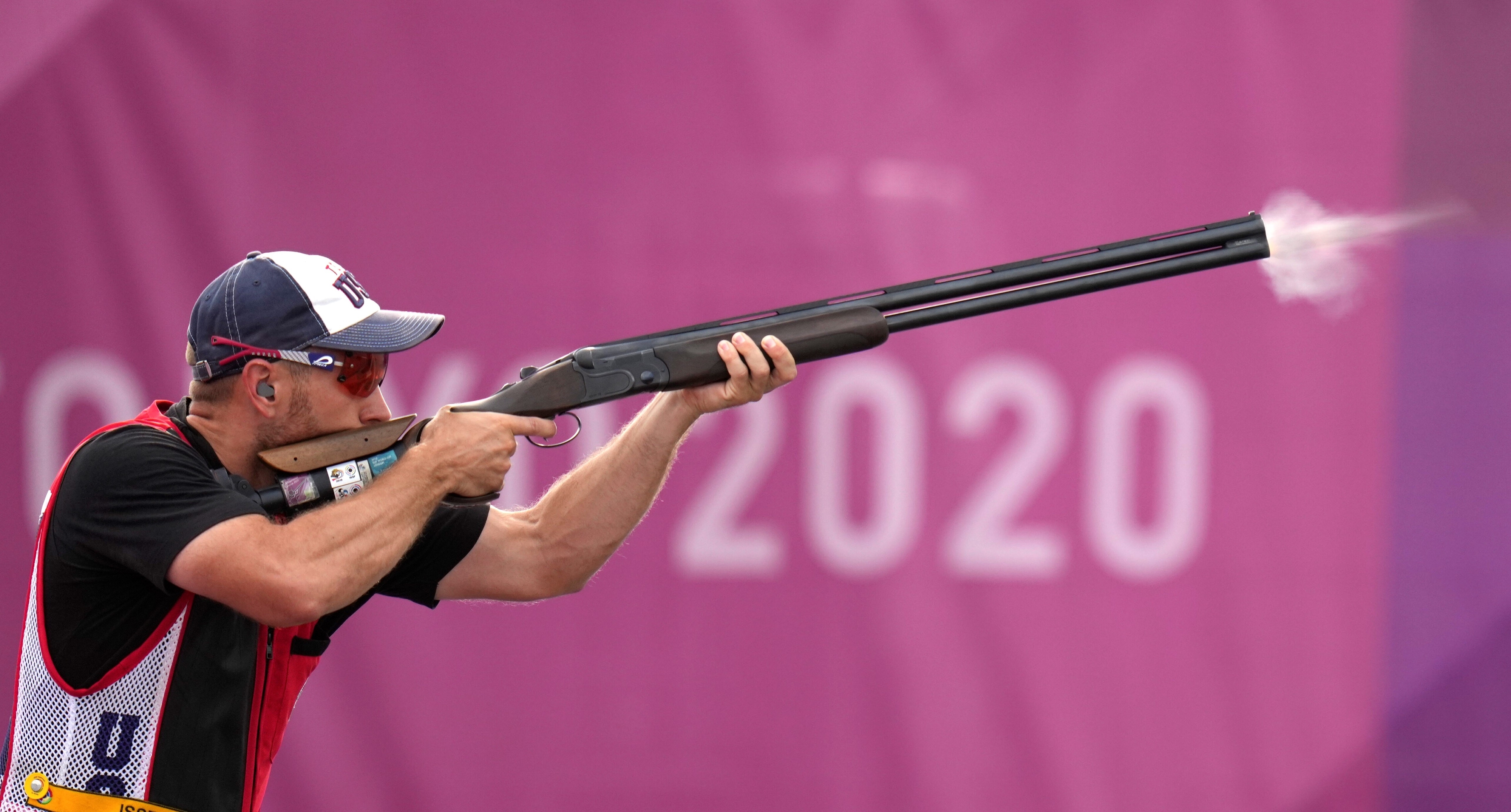 An athlete aims a shotgun while participating in the 2020 Olympic Games shooting event.