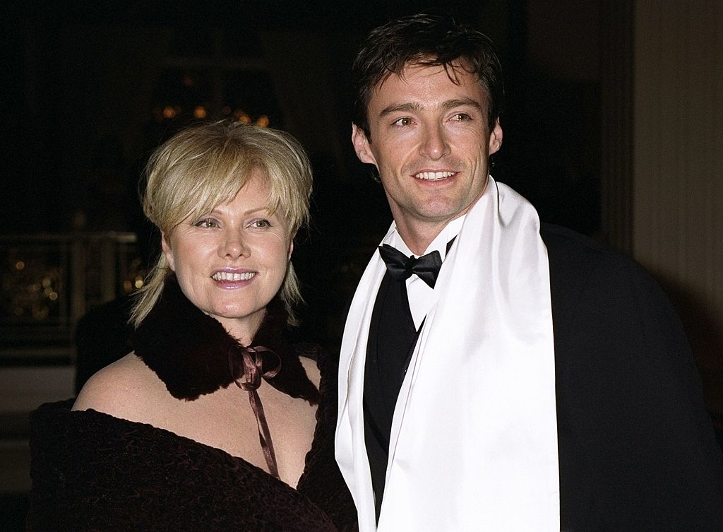 Deborra-Lee Furness and Hugh Jackman dressed in elegant evening wear, with Hugh in a tuxedo and a white scarf, posing together at a formal event