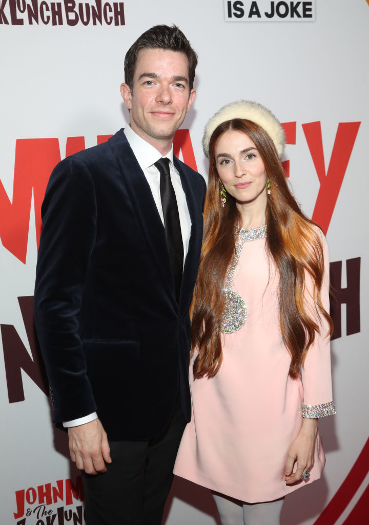 John Mulaney in a suit and Annamarie Tendler in a pink dress with a jeweled detail and a fur hat at a red carpet event