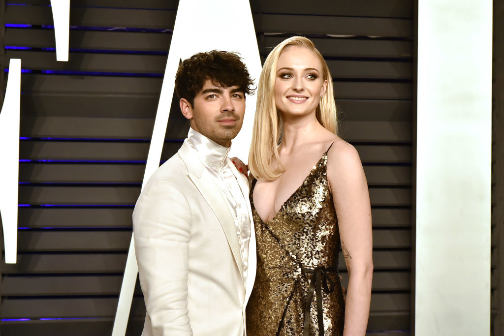 Joe Jonas in a white suit, standing beside Sophie Turner in a sparkling gown at a formal event