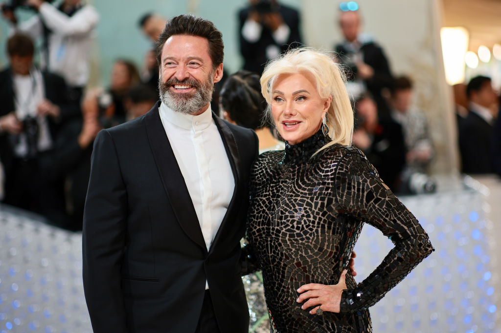 Hugh Jackman in a tailored suit and Deborra-Lee Furness in a patterned dress pose together at a formal event