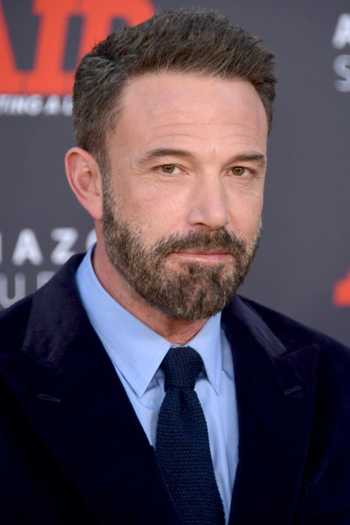 Ben Affleck on the red carpet in a formal suit and tie, looking directly at the camera