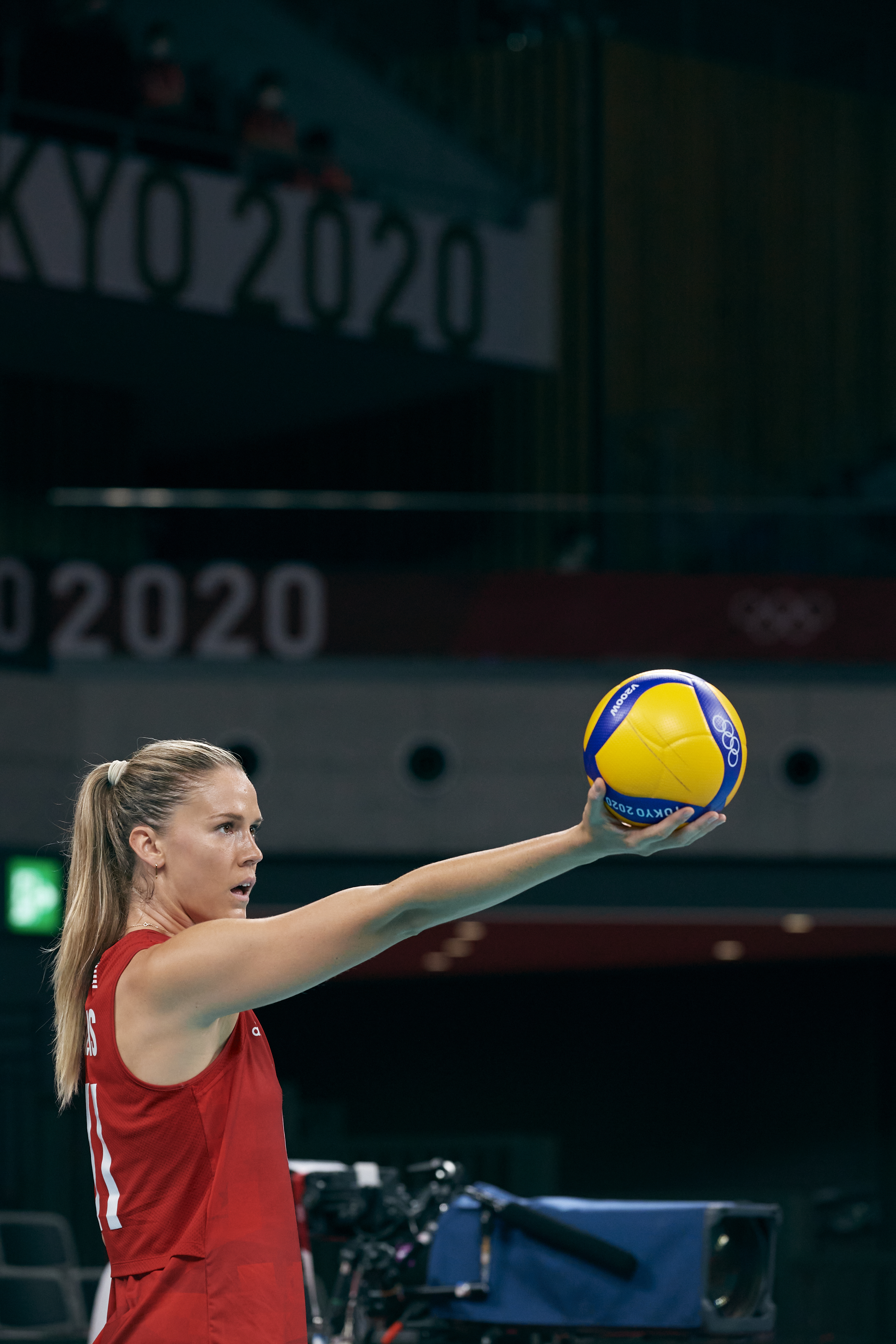 Female volleyball player in a red jersey prepares to serve at Tokyo 2020 Olympics