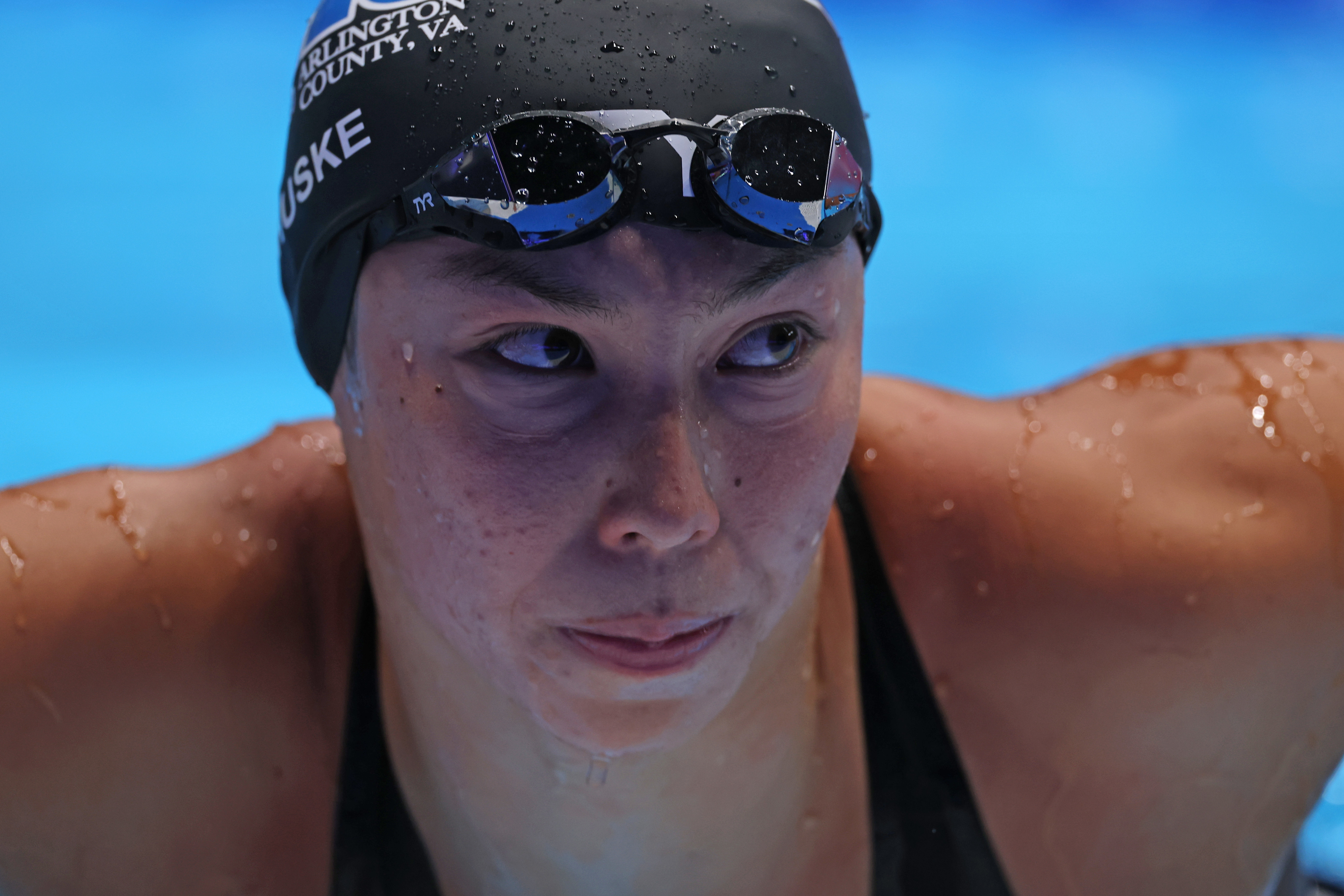 Torri Huske, wearing swim goggles and cap, appears focused after a swim in a competitive pool setting