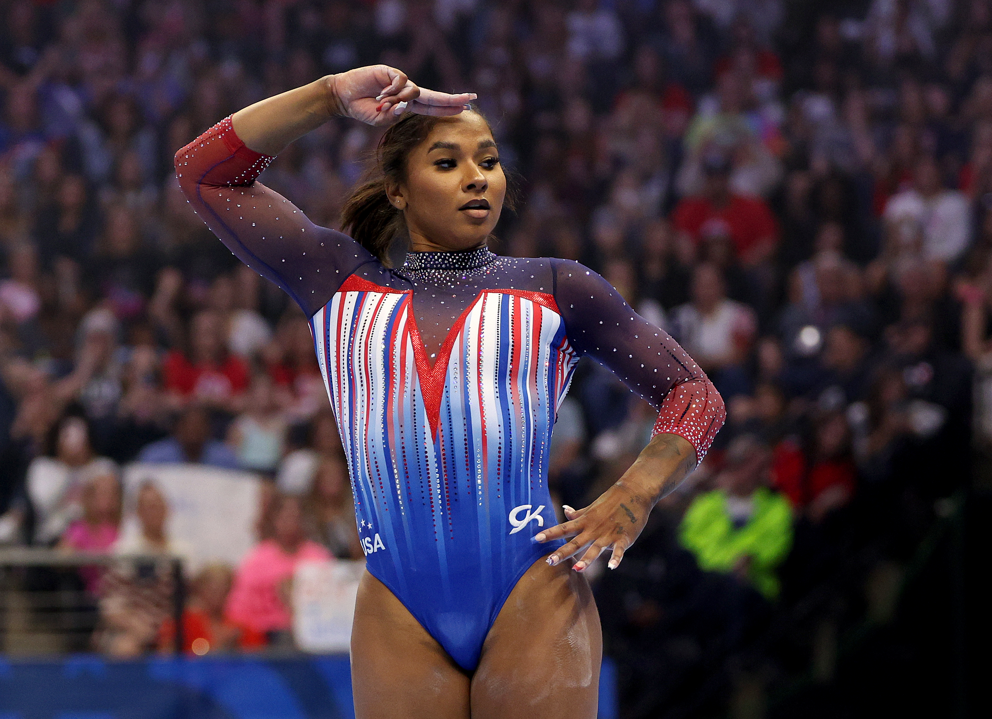 Gymnast Nia Dennis performs her routine at a gymnastics event, wearing a vibrant leotard with intricate patterns and the USA emblem