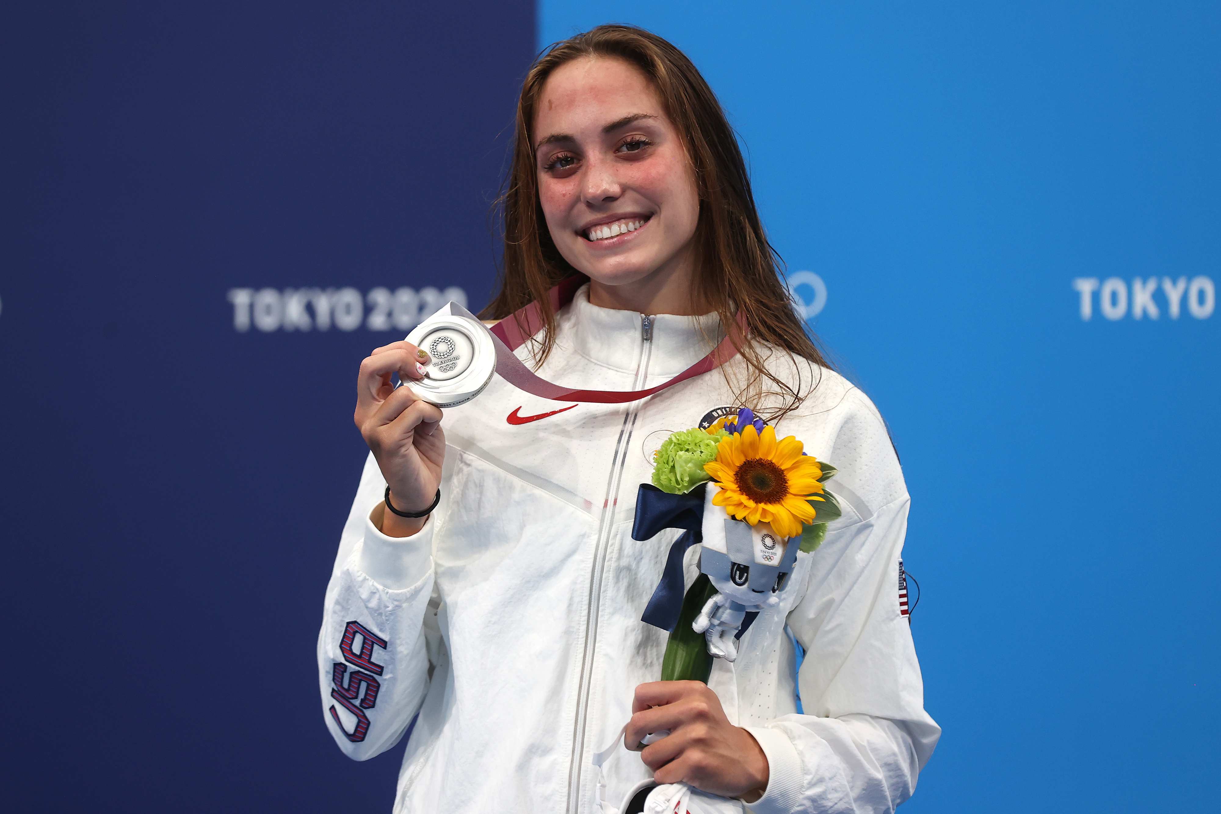 An Olympic athlete in Team USA attire holds a silver medal and a bouquet of sunflowers at the Tokyo 2020 Olympics