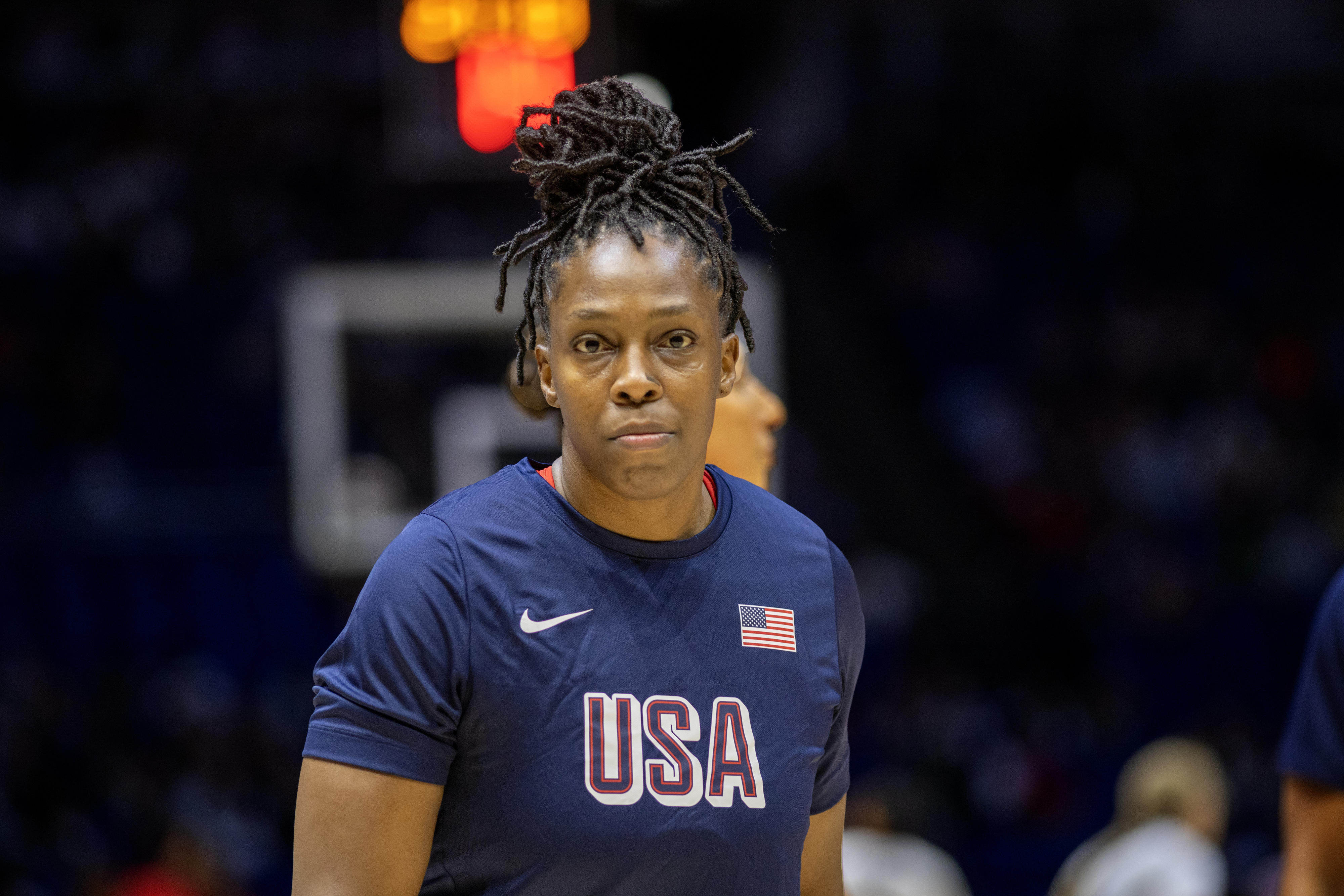 A basketball player dons a USA jersey on the court, preparing for the game