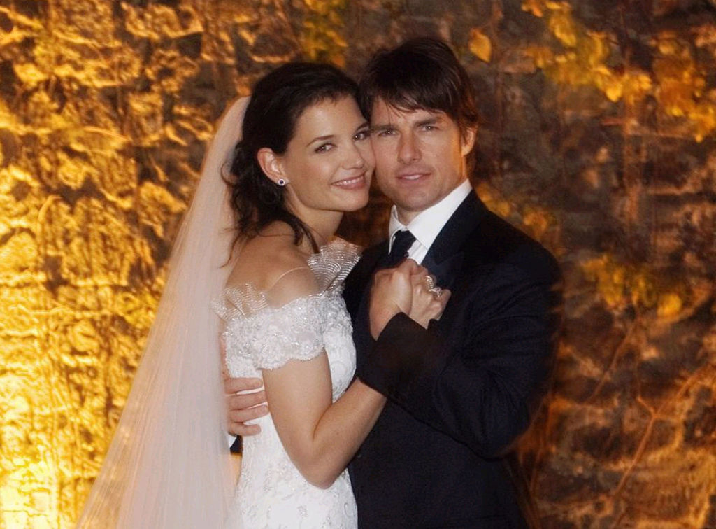 Katie Holmes and Tom Cruise, dressed in wedding attire, pose together with smiles