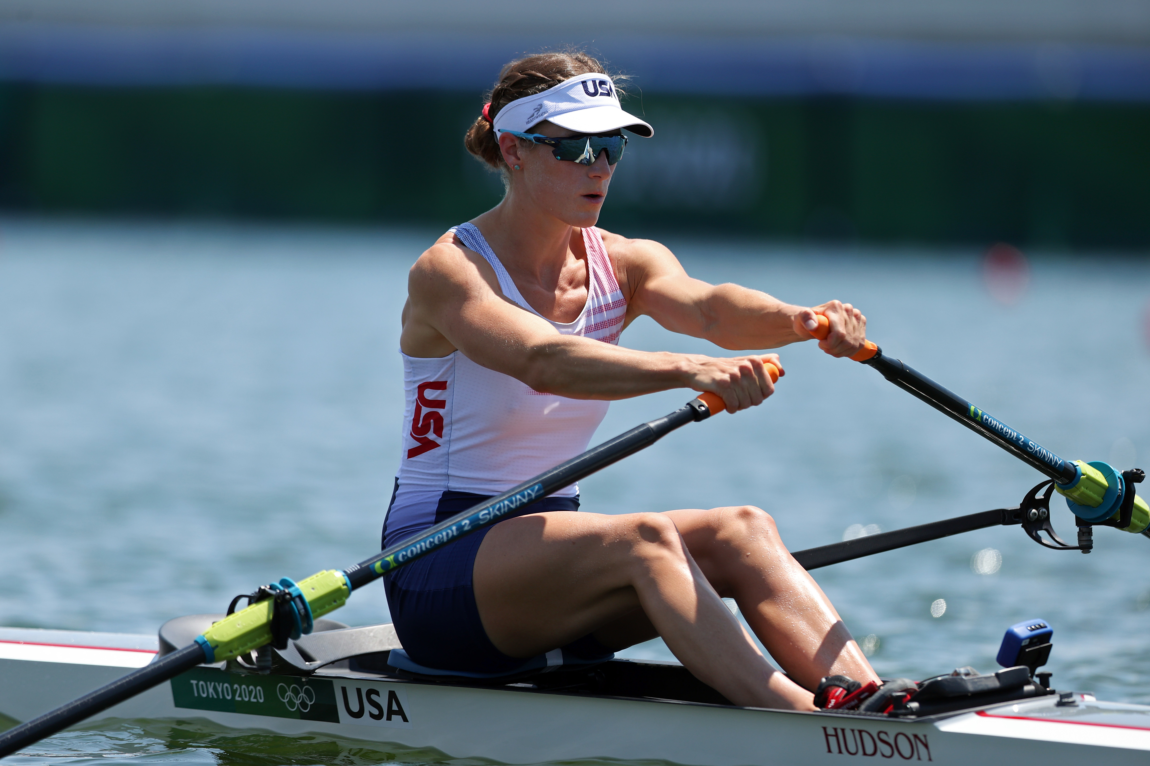 Rowing athlete Kara Kohler on water in Tokyo 2020 Olympics, wearing a Team USA uniform and visor, focused while rowing