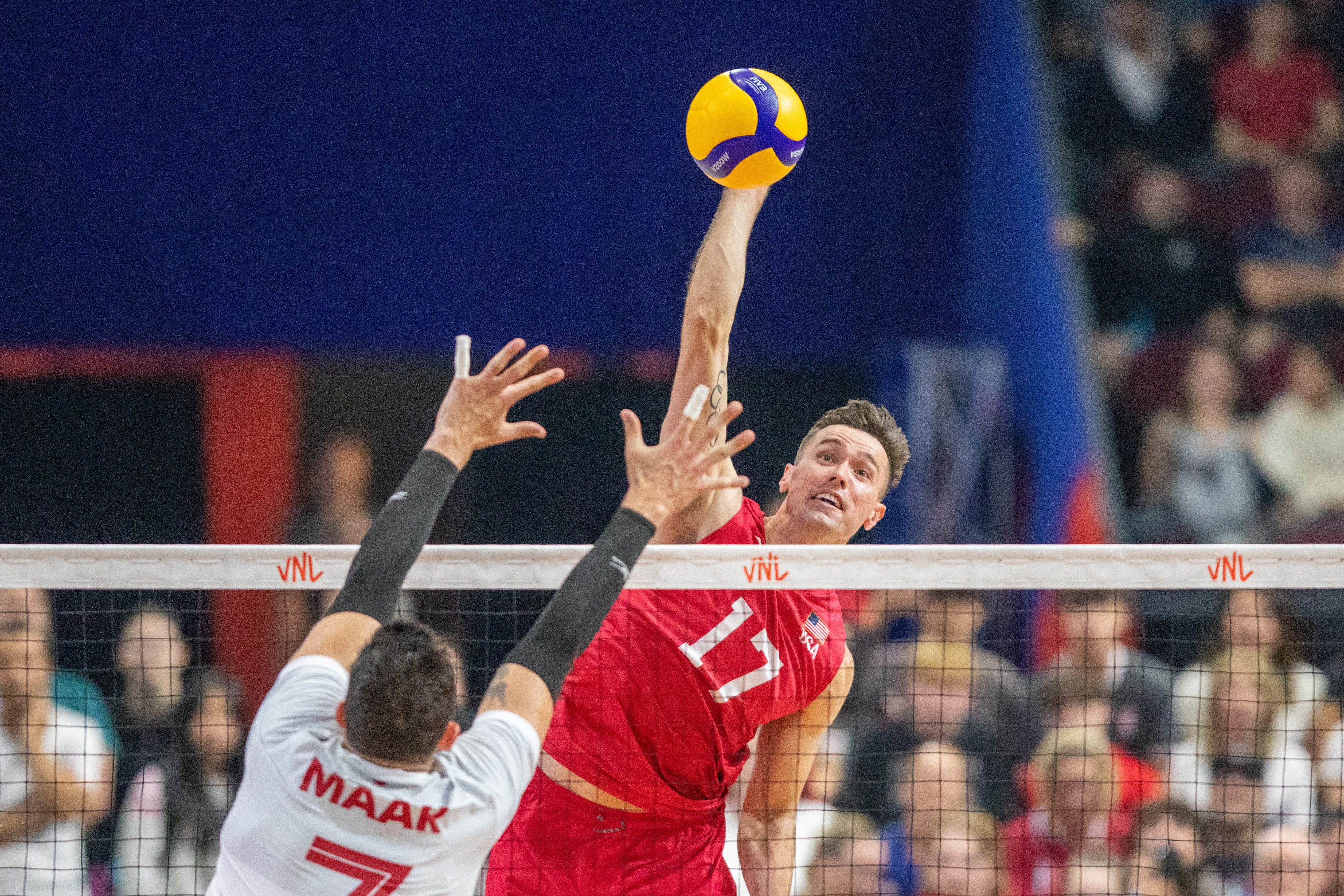Volleyball player #17 spikes the ball over opponent #7 in an action-packed match at the Volleyball Nations League