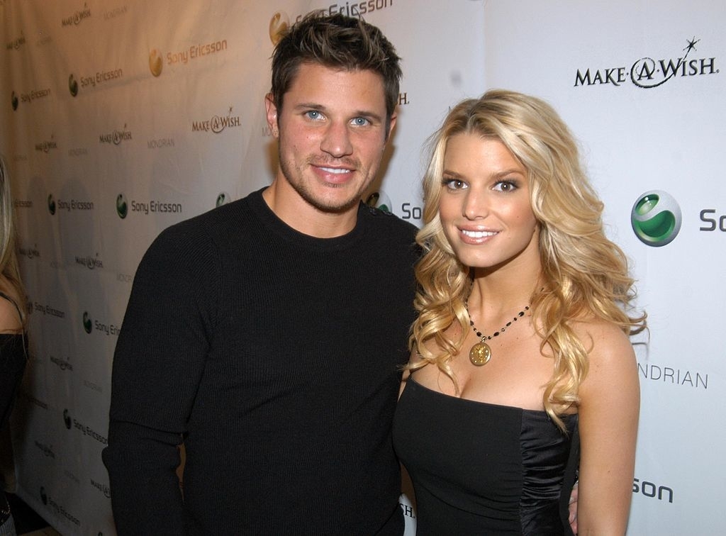 Nick Lachey and Jessica Simpson pose together at a Make-A-Wish event. Nick wears a black sweater, and Jessica wears a strapless black dress