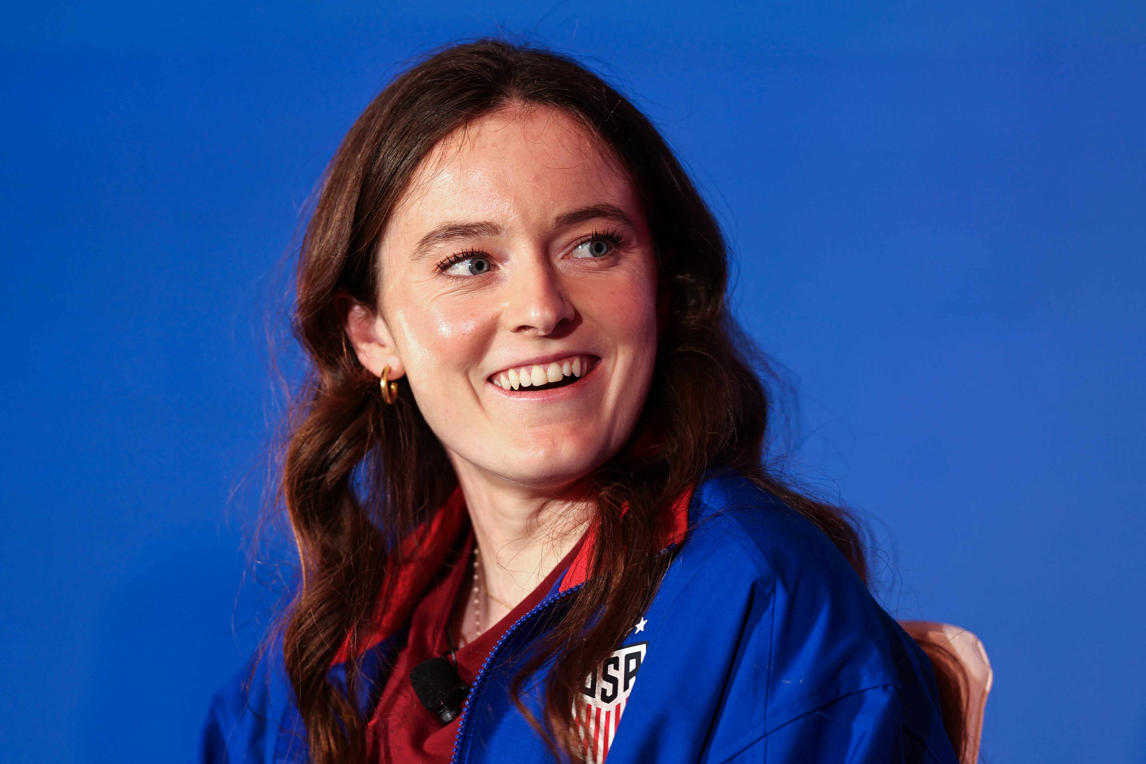 Kelley O’Hara, wearing a USA soccer jacket, smiles during an event