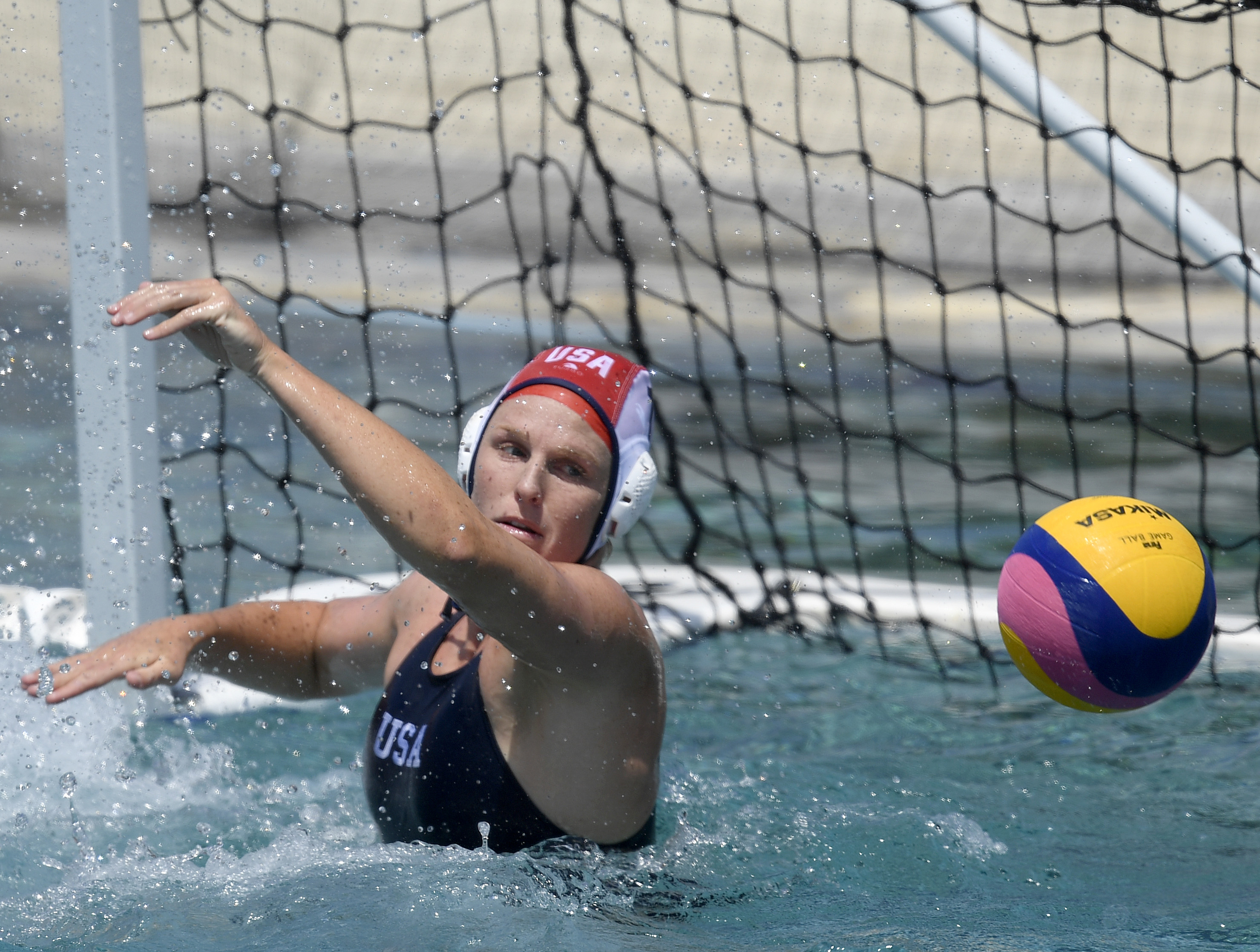 Amanda Longan in action, blocking a multicolored ball in front of the goal