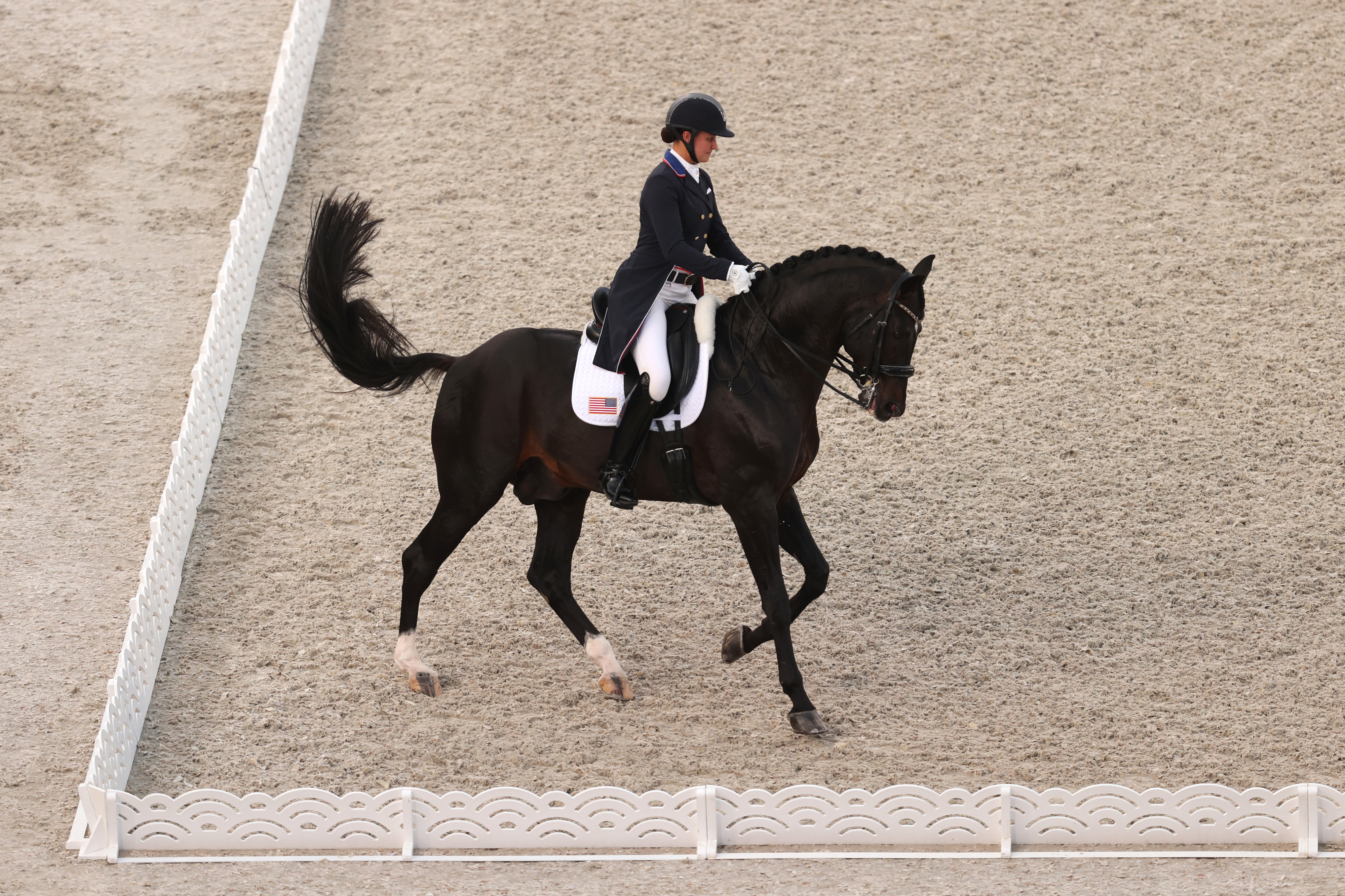 Adrienne Lyle in full gear on a horse performs during a competition on a sandy arena
