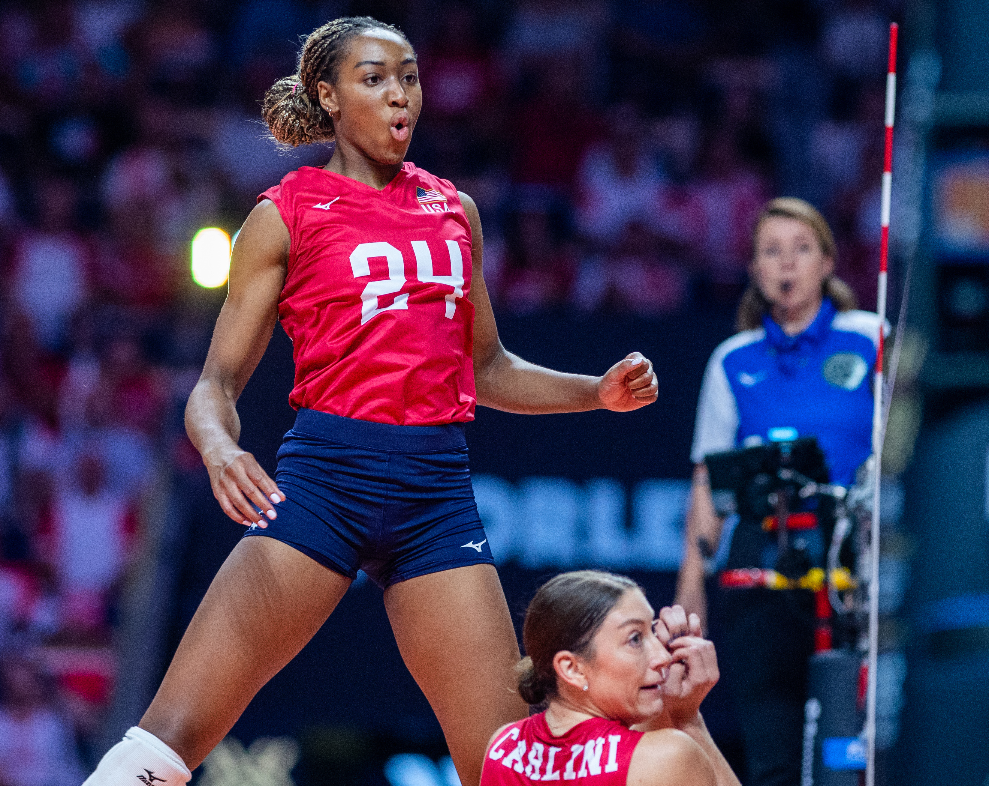 Volleyball players in action during a match, with 24 shown mid-jump.