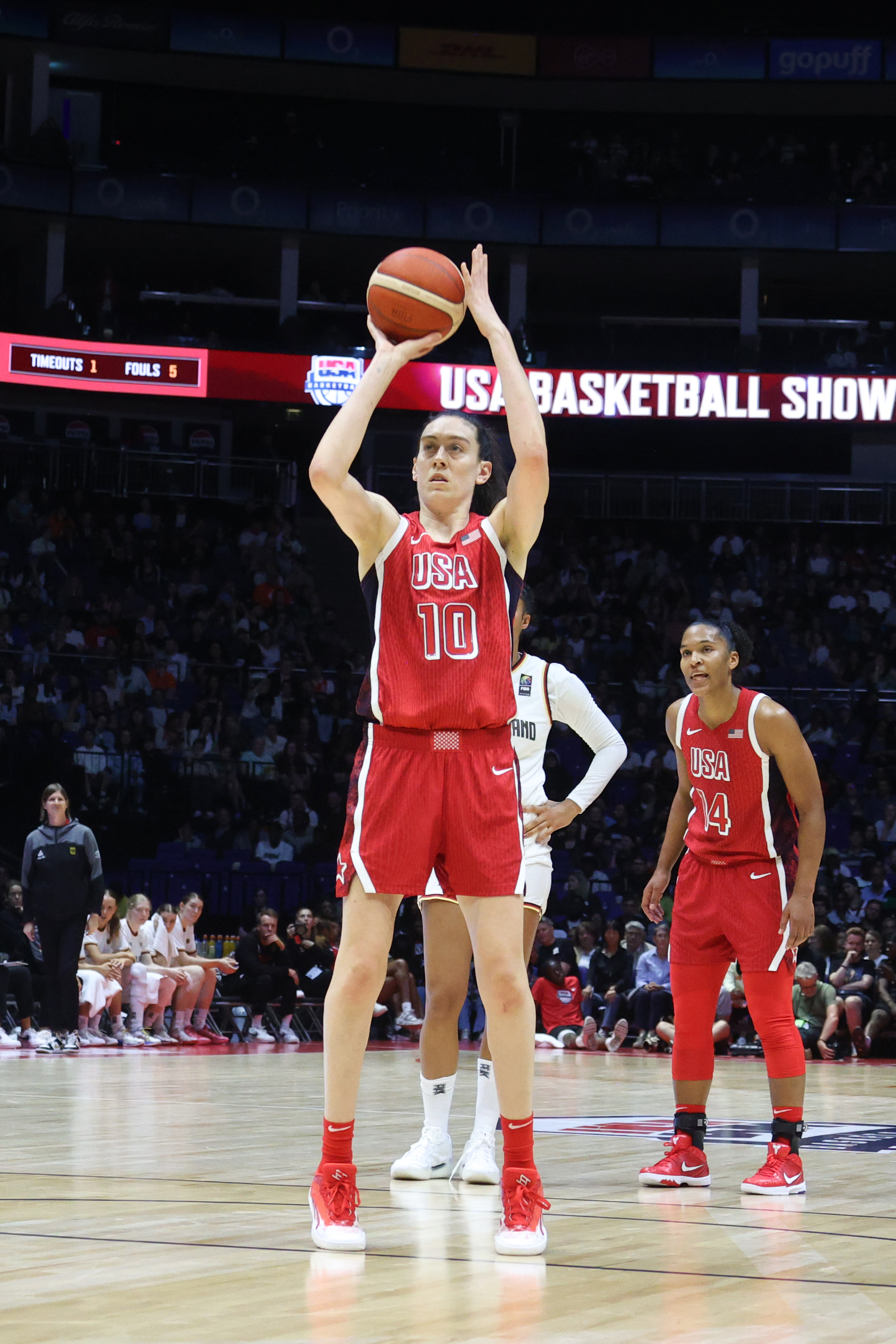 A basketball player wearing a red &quot;USA&quot; jersey with the number 10 is seen preparing to take a free throw, while another player, number 14, stands nearby