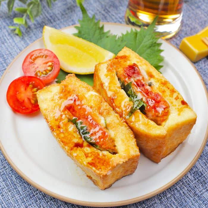 お皿の上に厚揚げ料理とミニトマトのスライス、レモンウェッジが盛り付けられている。