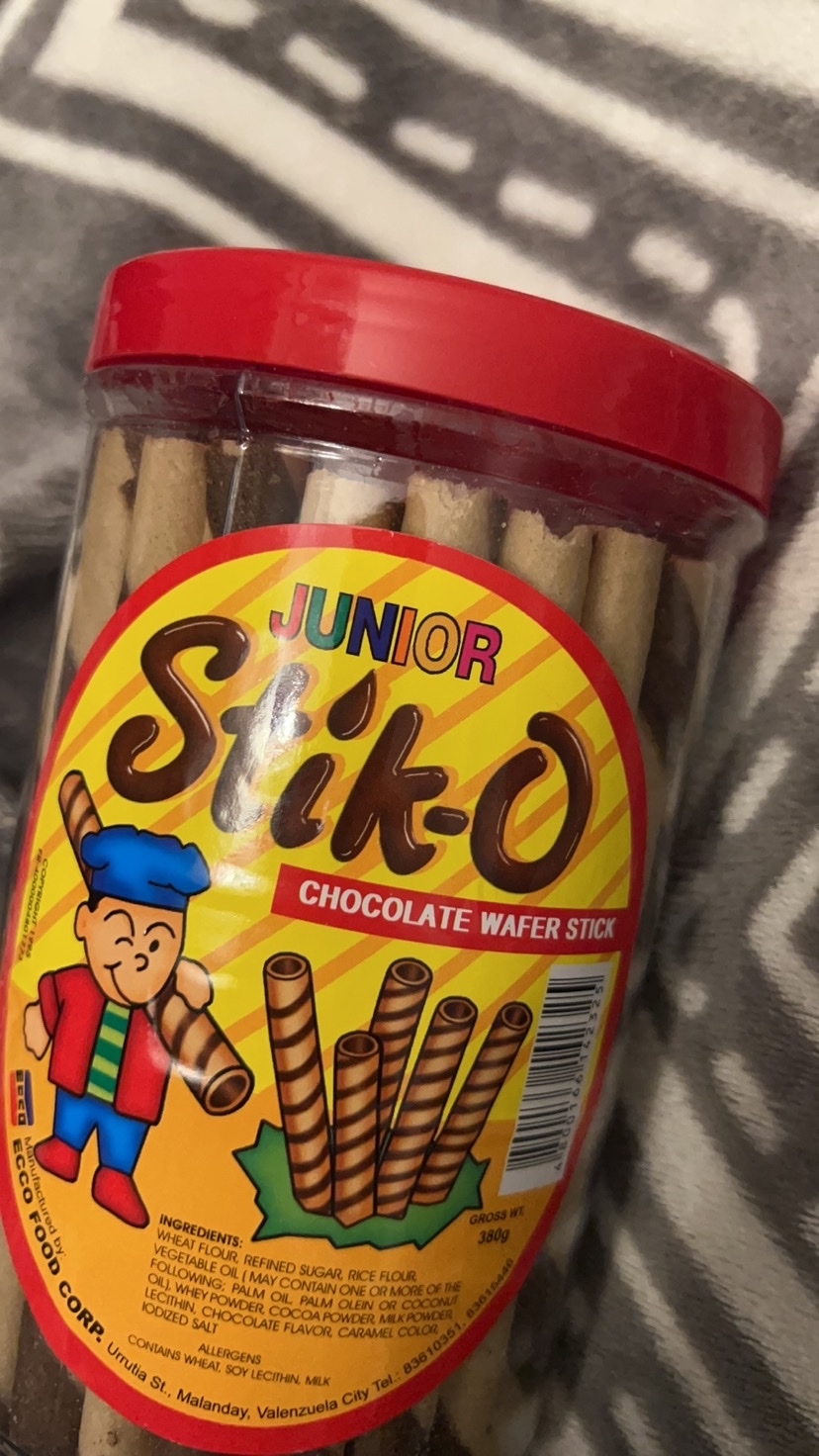 Jar of Junior Stik-O chocolate wafer sticks with a cartoon character on the label. The jar has a red lid and the label displays product information and ingredients
