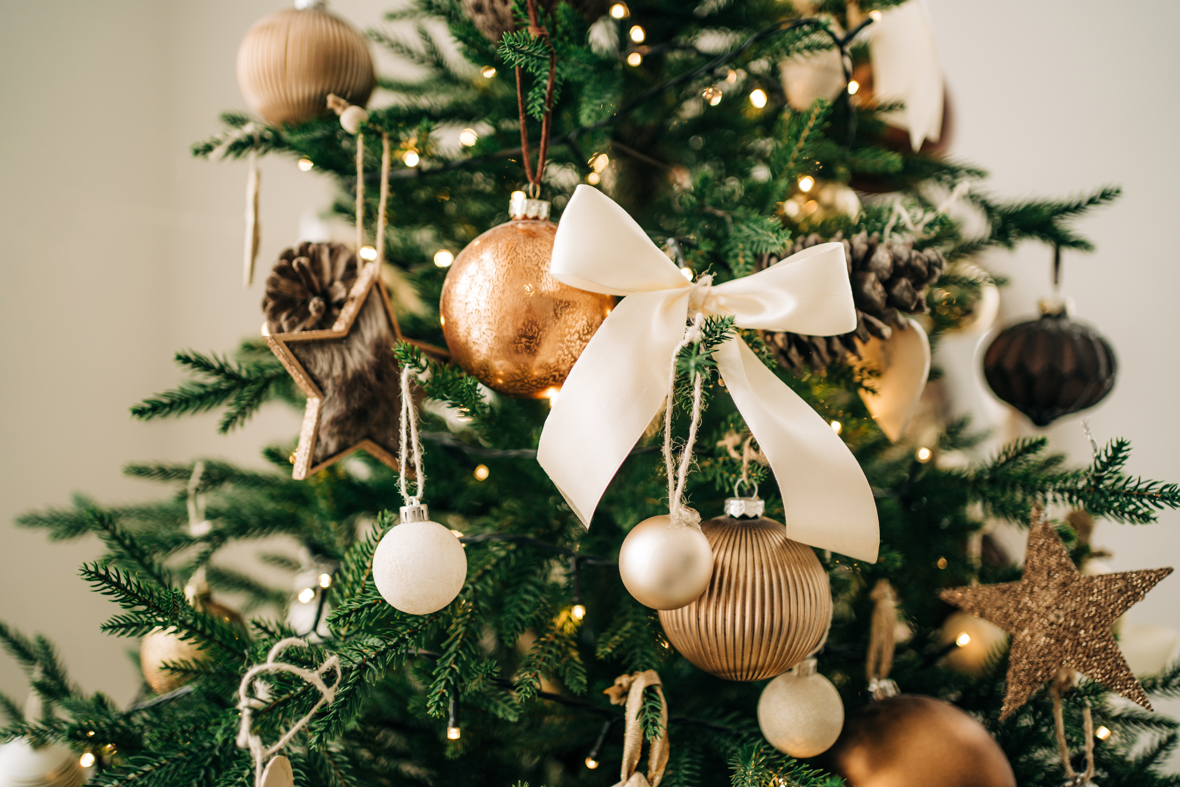 Christmas tree decorated with ornaments, including stars, balls, pinecones, and a large bow. There are no people in the image