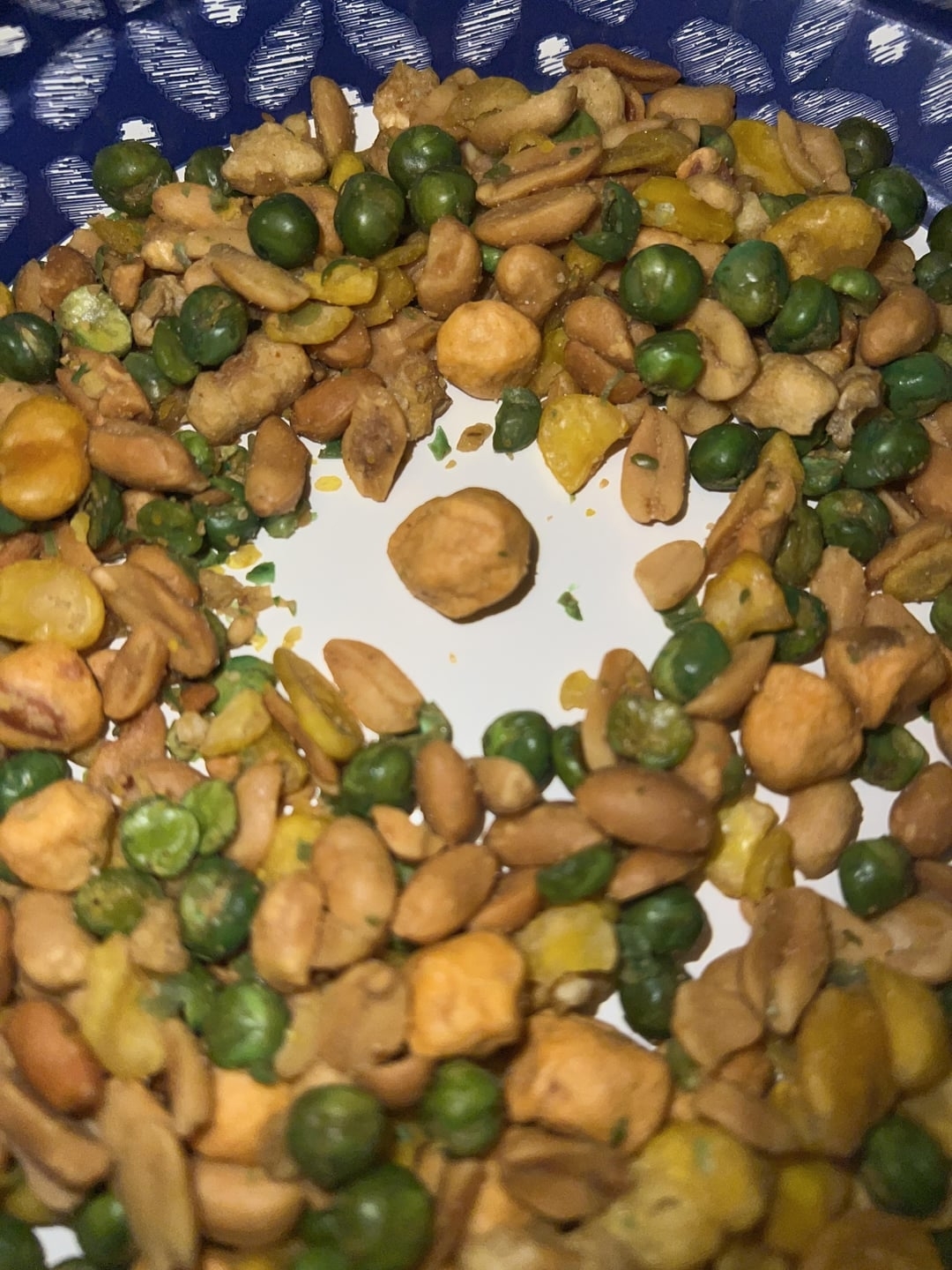 Mixed nuts, peas, and corn on a white plate with a blue patterned rim