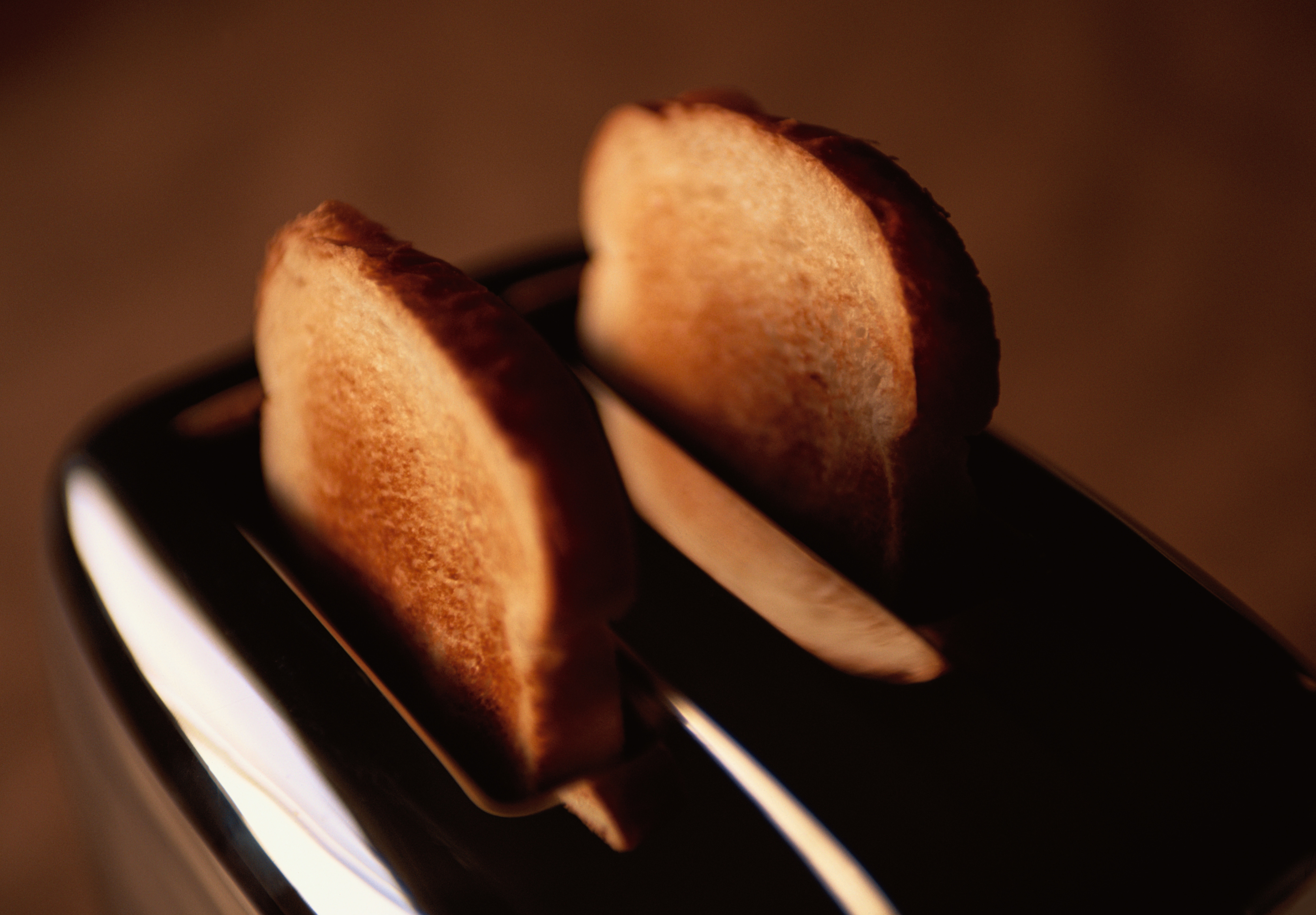 Two slices of toasted bread popping out of a shiny toaster