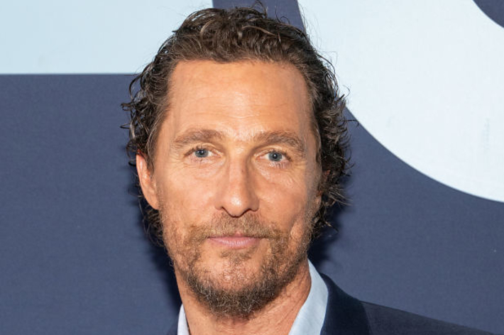 マシュー・マコノヒーがスーツを着てカメラに向かって微笑んでいる。背景は無地の壁。