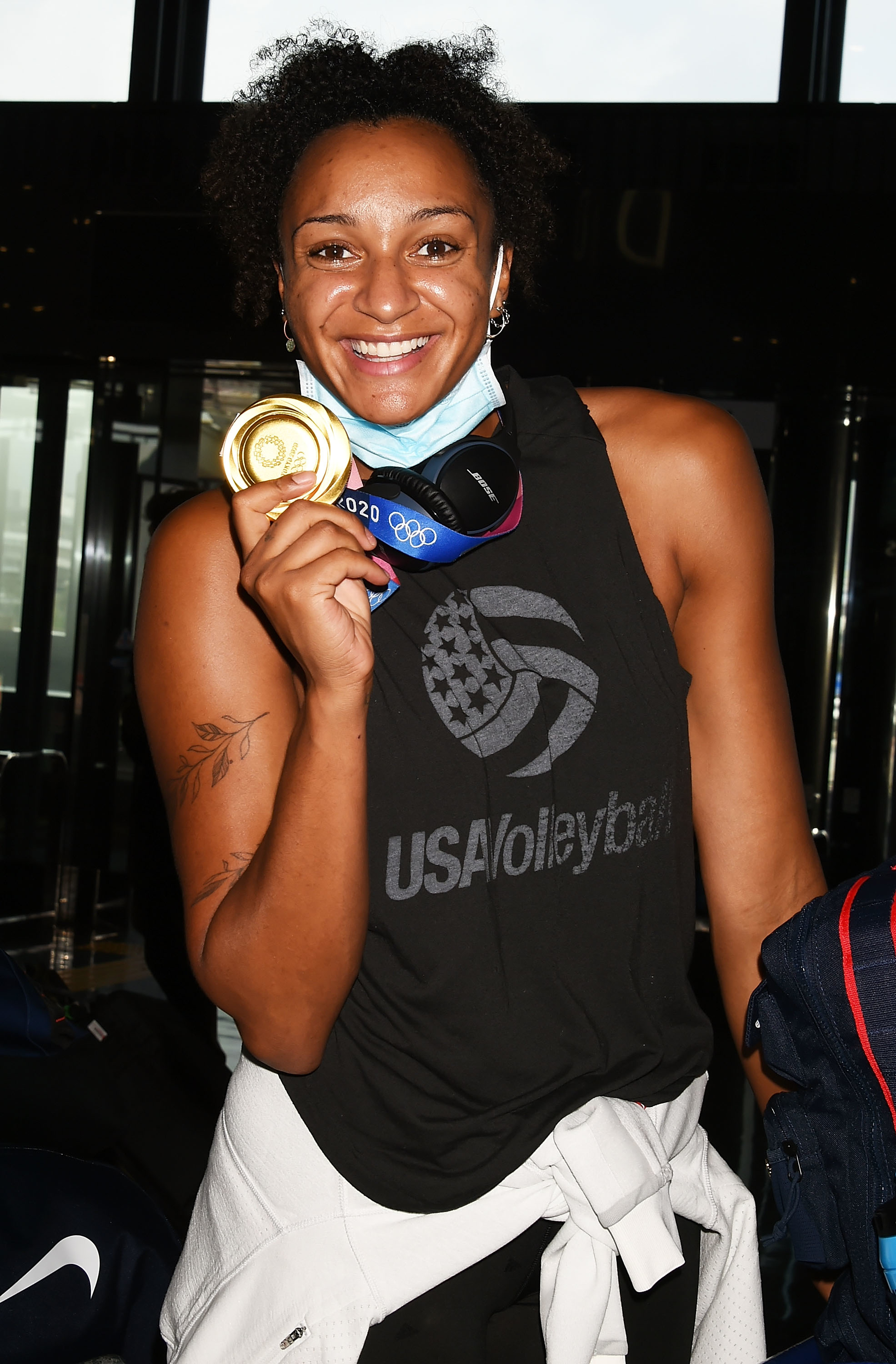 U.S. volleyball player Jordan Larson smiles while holding her gold medal. She is wearing a sleeveless USA Volleyball shirt