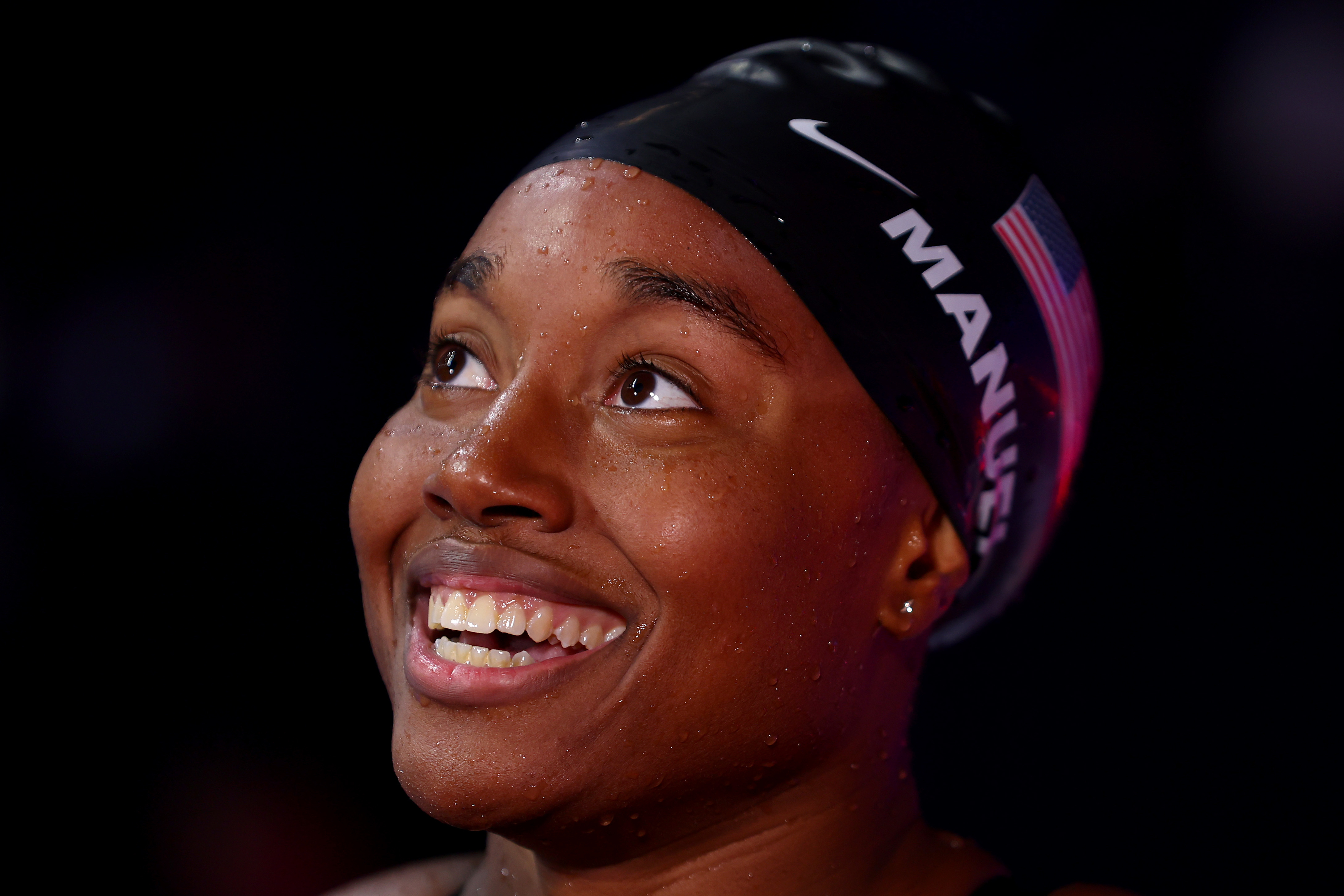 Simone Manuel, wearing a swim cap with her name and a U.S. flag, smiles after a race
