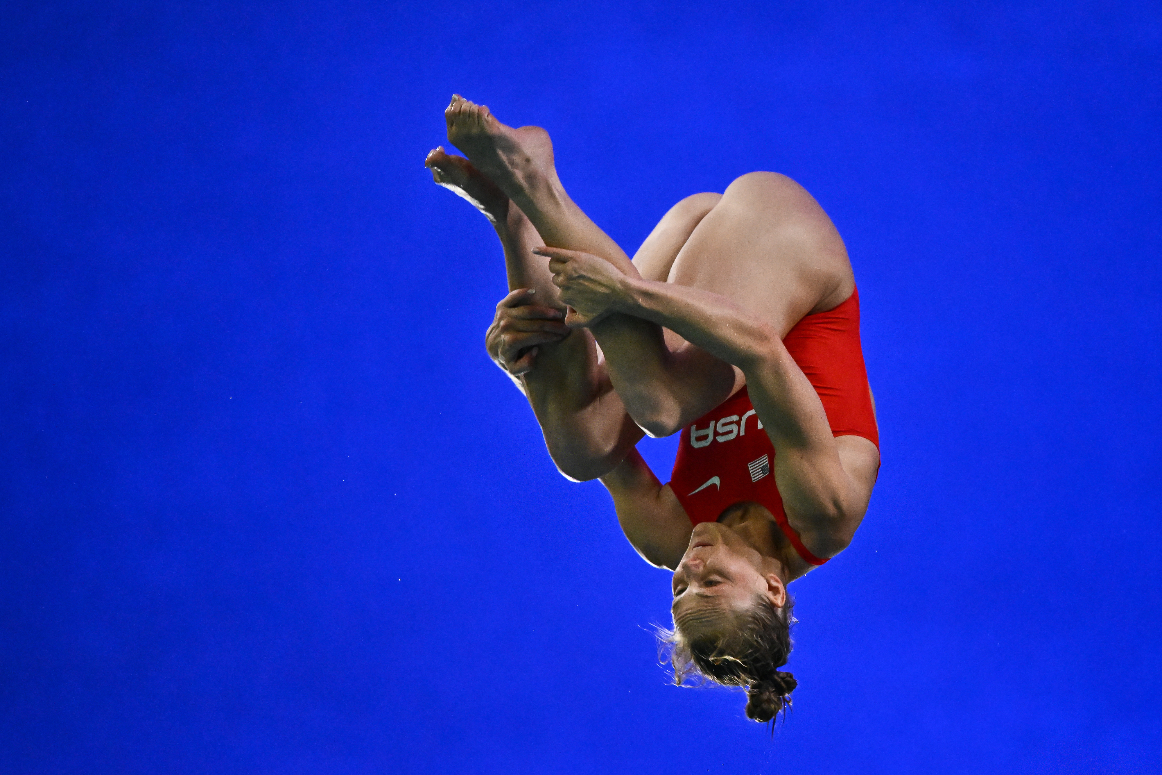 Delaney Schnell wearing a USA jersey performs a mid-air flip during a gymnastic or diving routine