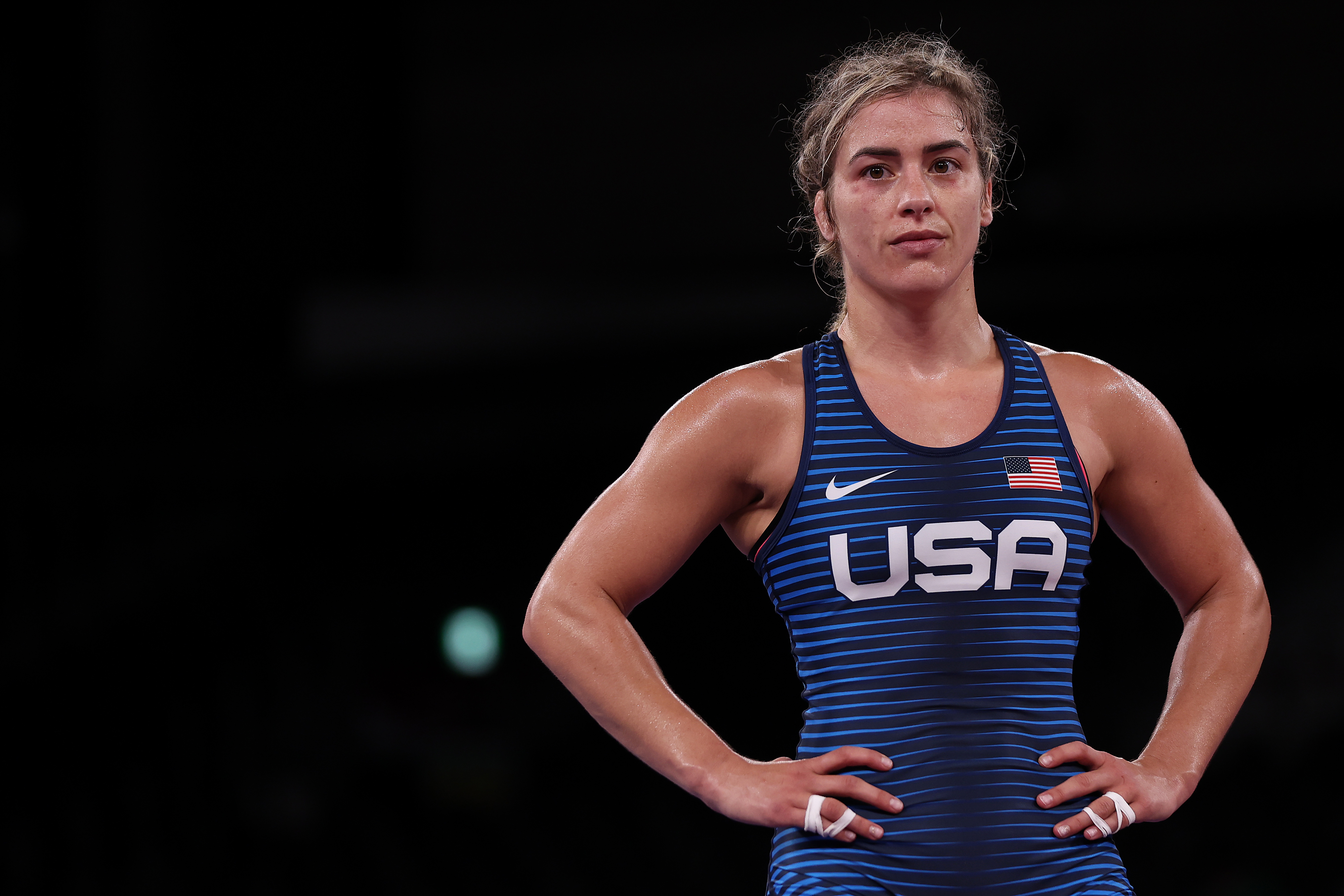 Wrestler in a USA singlet, hands on hips, looking determined during a sports event