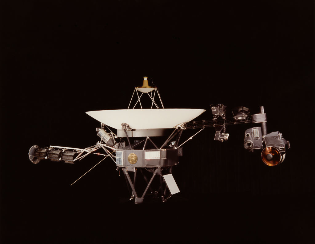 Image of a NASA spacecraft, Voyager 1, featuring its large dish-shaped antenna and various scientific instruments extending from its body