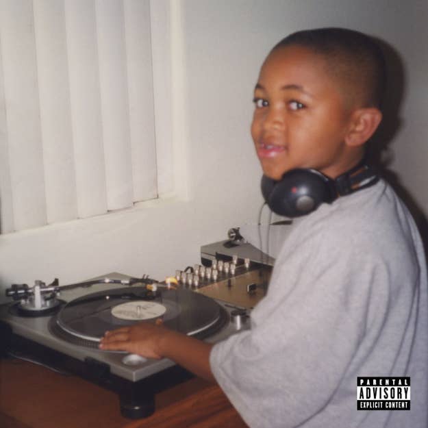 A young boy wearing headphones stands next to a turntable, looking at the camera. Explicit content warning label in the bottom right corner