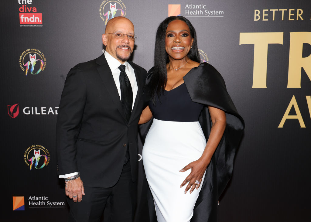 Vincent Hughes and Sheryl Lee Ralph on the red carpet at an event. Sheryl Lee Ralph is wearing a stylish dress with cap, Vincent Hughes is in a classic suit and tie