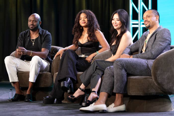 Wayne Brady, Maile Brady, Mandie Taketa, and Jason Michael Fordham sit on a panel, dressed in stylish, casual outfits, speaking at a public event
