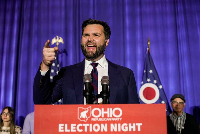 J.D. Vance speaks passionately on stage at an Ohio Republican Party event, behind a podium with the text "Ohio Election Night". Multiple microphones are in front of him