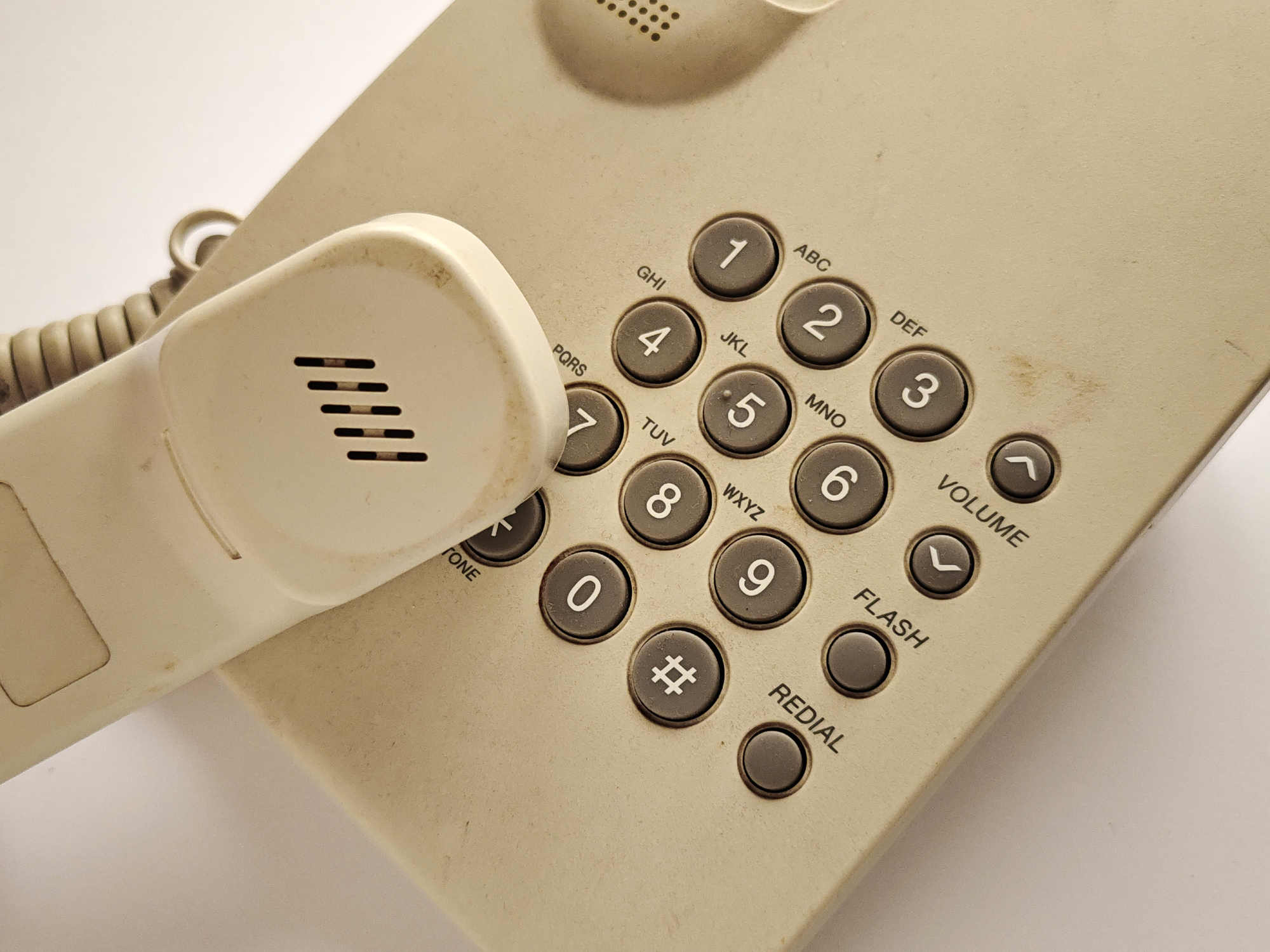 A close-up of an old-fashioned corded telephone with a numeric keypad and receiver placed on the base