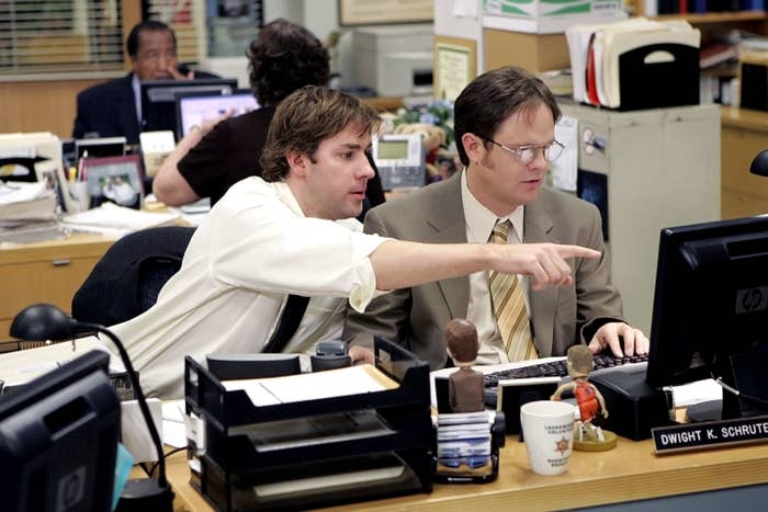 Jim Halpert points at a computer screen while Dwight Schrute types, seated at their office desks from the TV show &quot;The Office&quot;