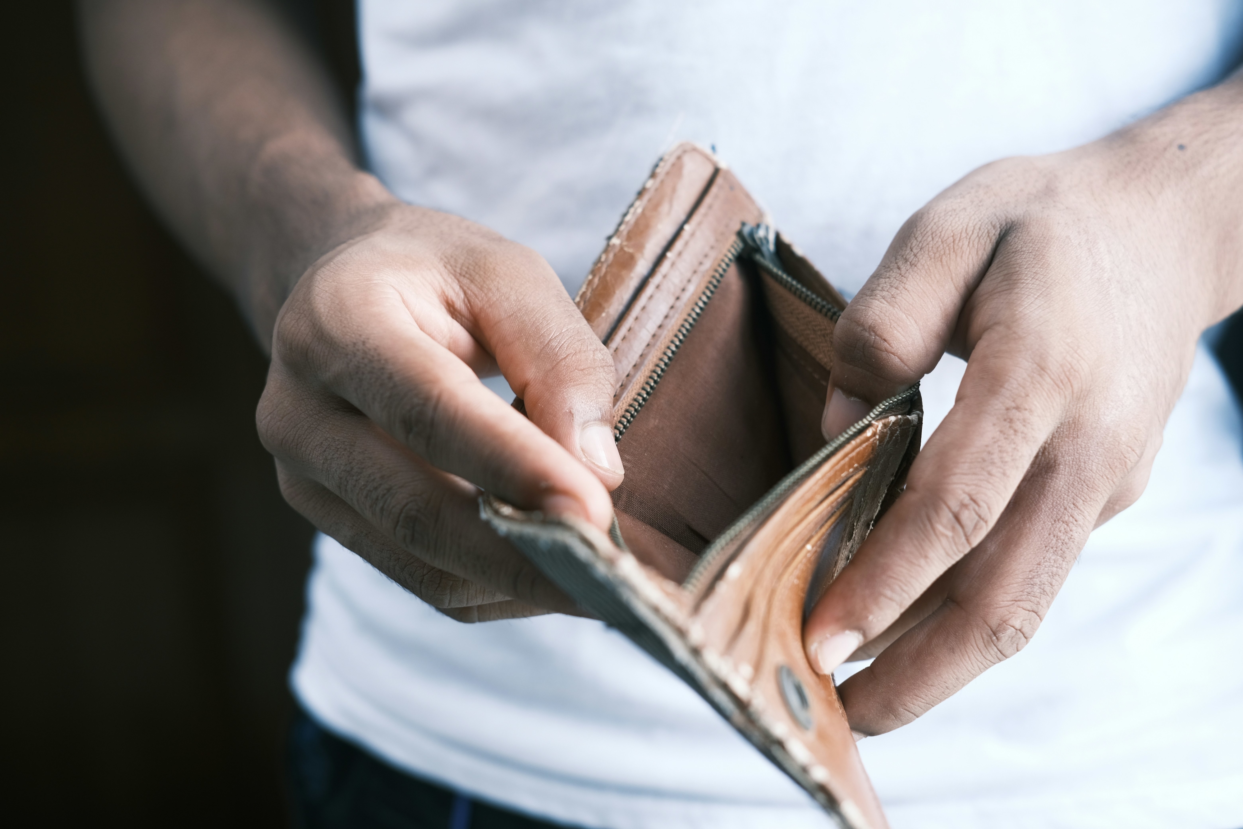Person holding an empty wallet with both hands, suggesting financial hardship