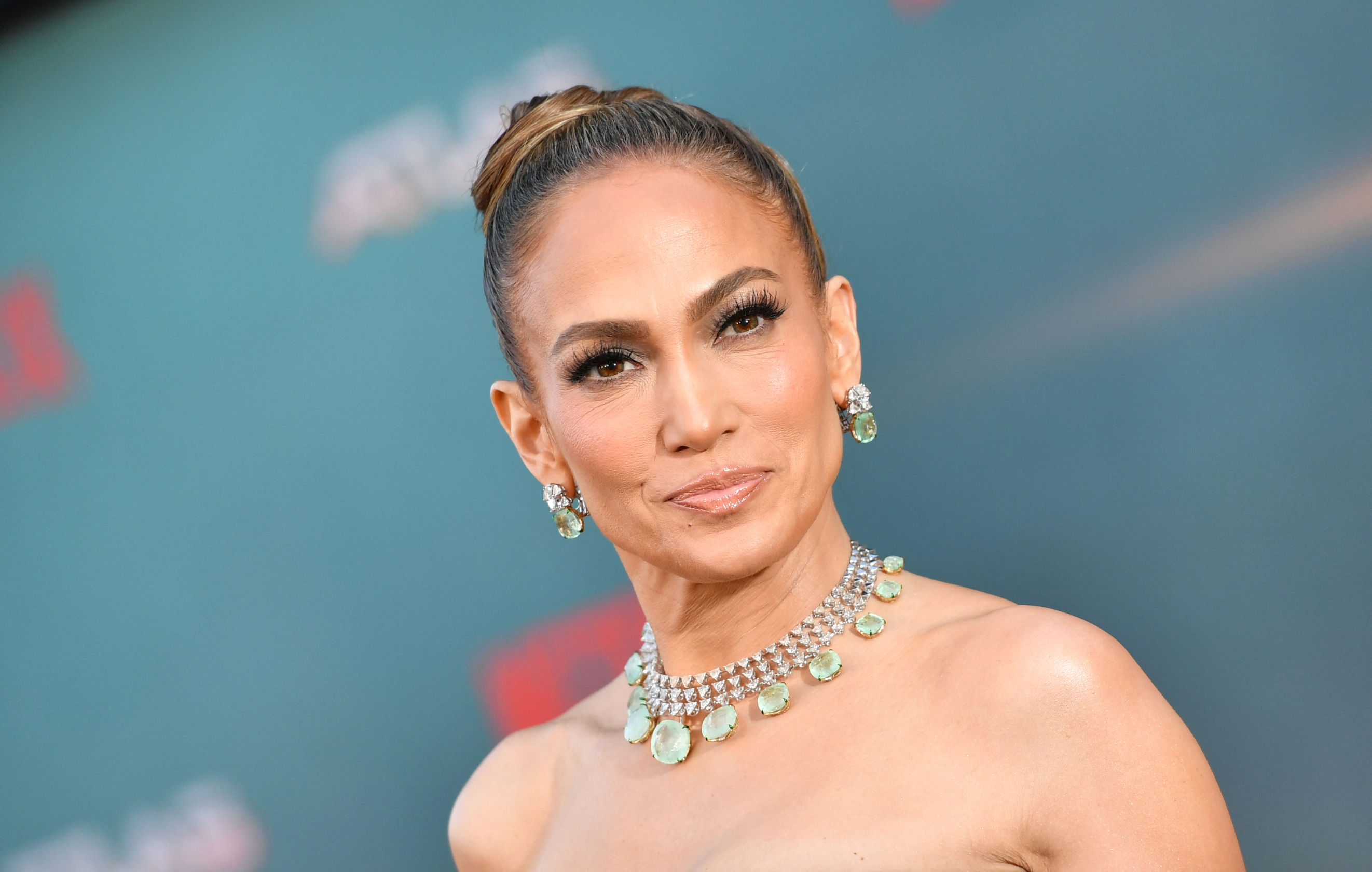 Jennifer Lopez poses on the red carpet, wearing a strapless gown and an elegant, layered necklace with matching earrings