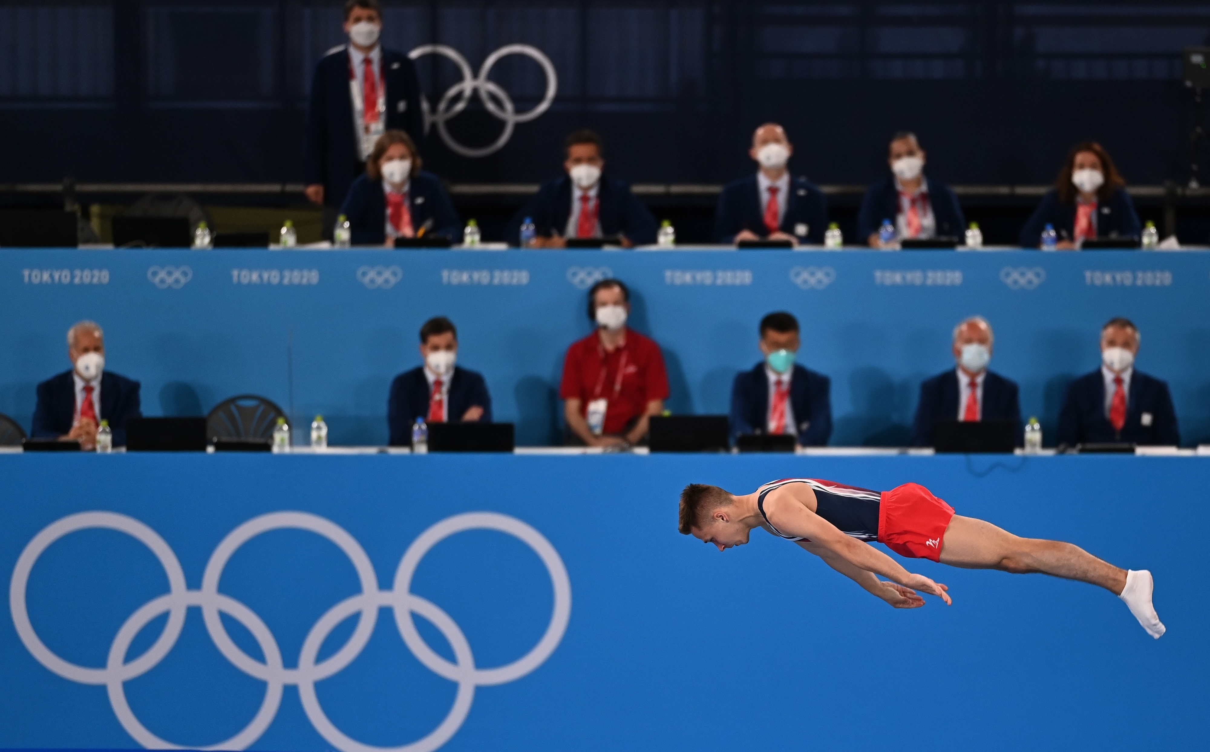 Athlete performs an acrobatic dive in front of judges during the Tokyo 2020 Olympics