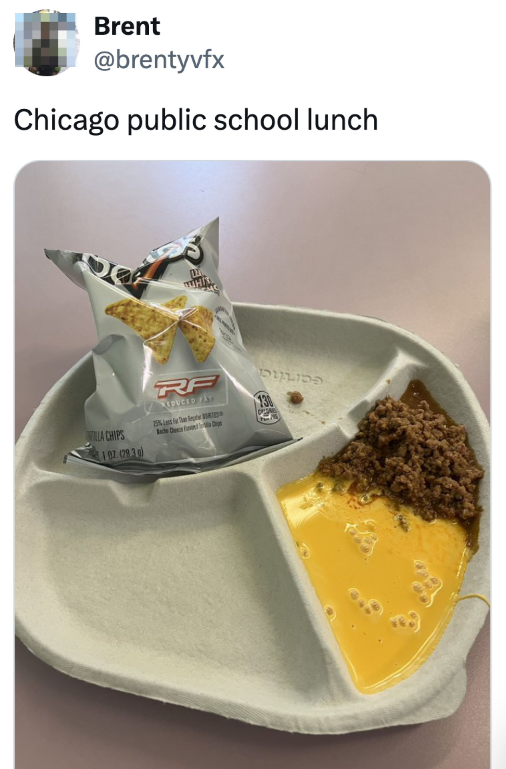 Disposable tray with nacho chips in a bag, unidentifiable meat, and a yellow liquid. Shared by Brent with the caption, "Chicago public school lunch."