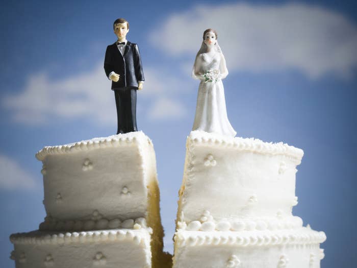 A wedding cake with plastic bride and groom figurines standing on two separate slices, symbolizing a marriage separation
