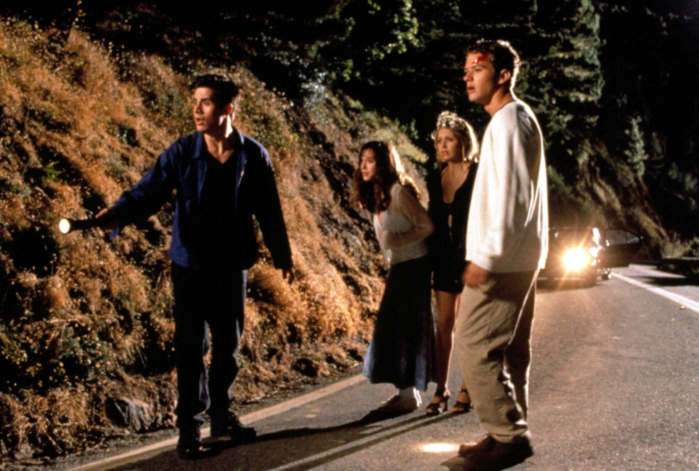 Freddie Prinze Jr., Jennifer Love Hewitt, Sarah Michelle Gellar, and Ryan Philippe standing in the middle of the street at night in a scene from &quot;I Know What You Did Last Summer&quot;