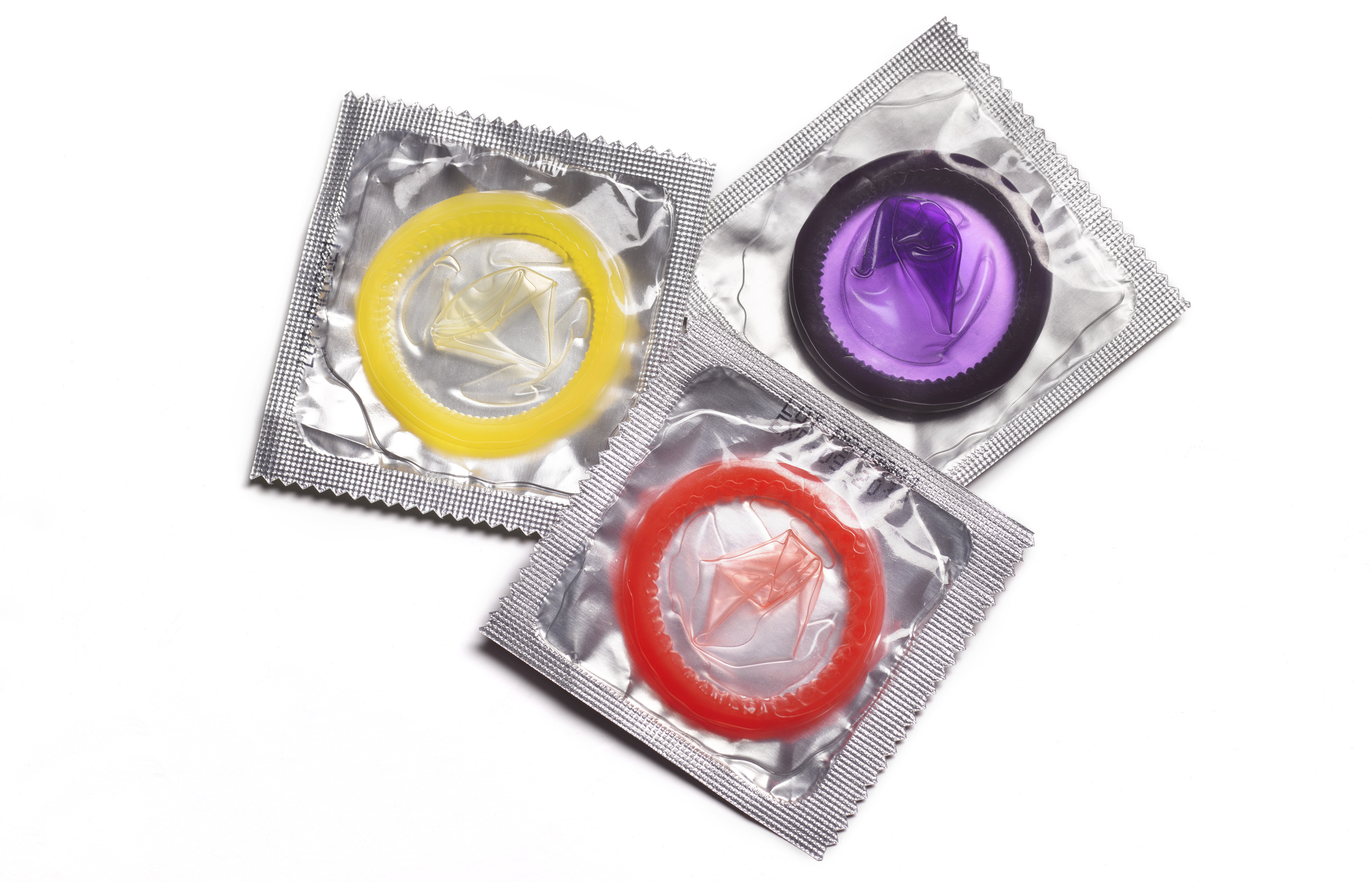 Three packaged condoms in yellow, purple, and red wrappers arranged in a triangle