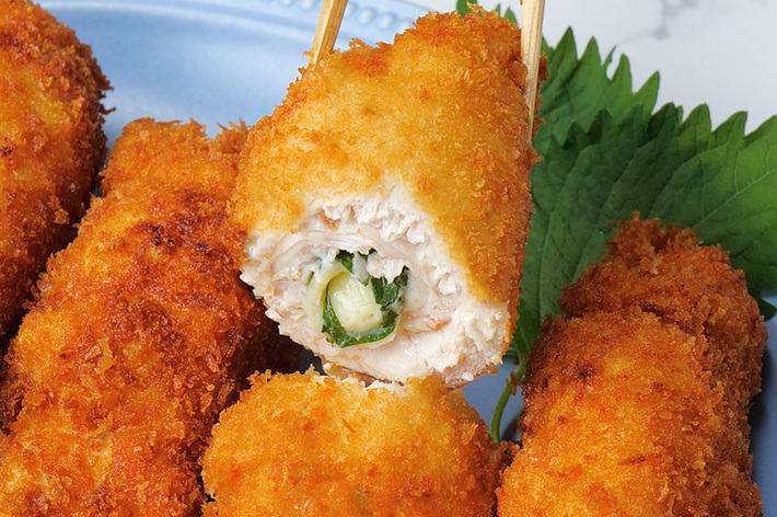 チキンカツロールが青い皿に盛られている。ロールの中身がチーズと野菜で満たされている。