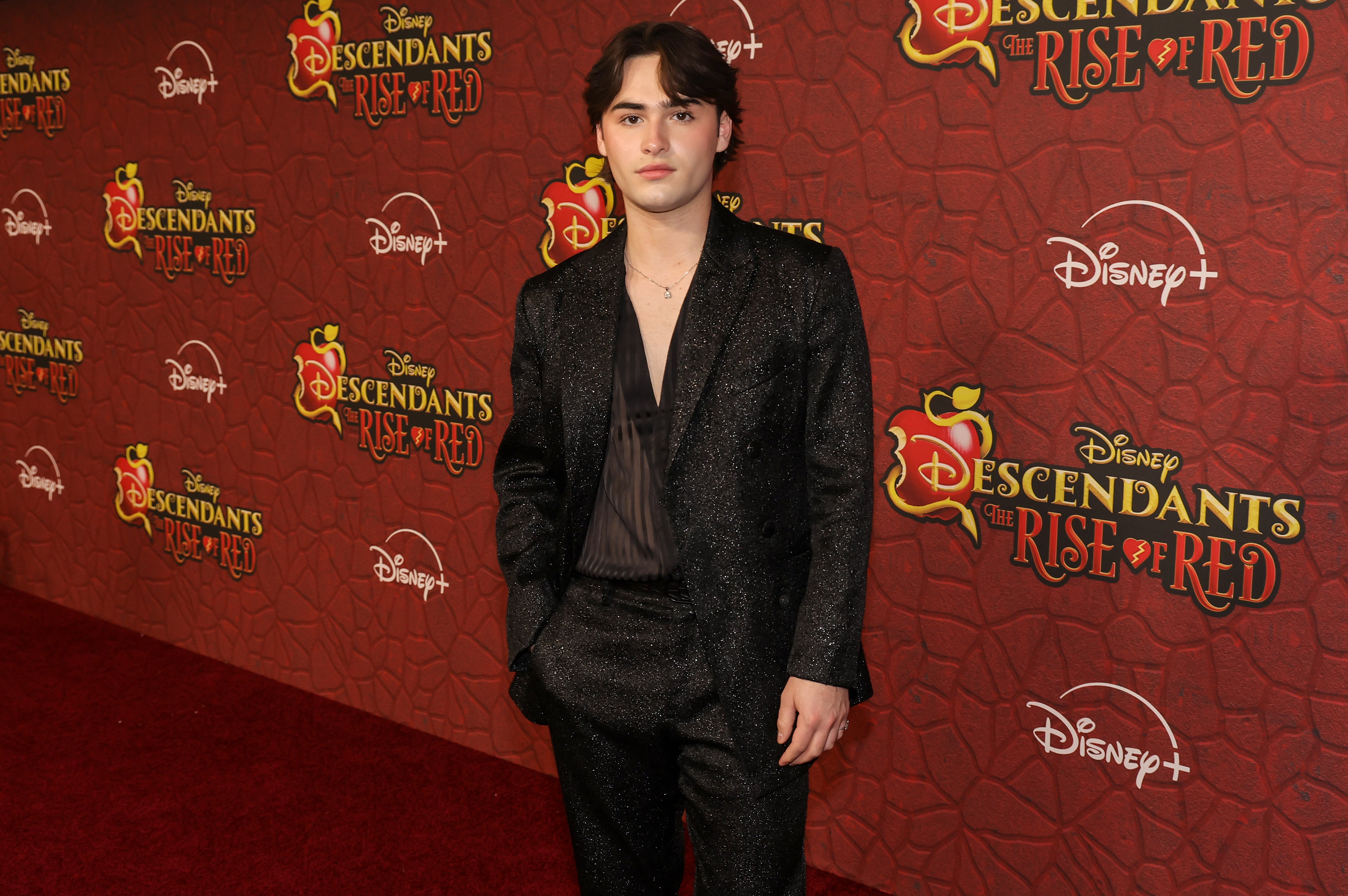 Joshua Colley on the red carpet for "Descendants: The Rise of Red" wearing a black shimmering suit