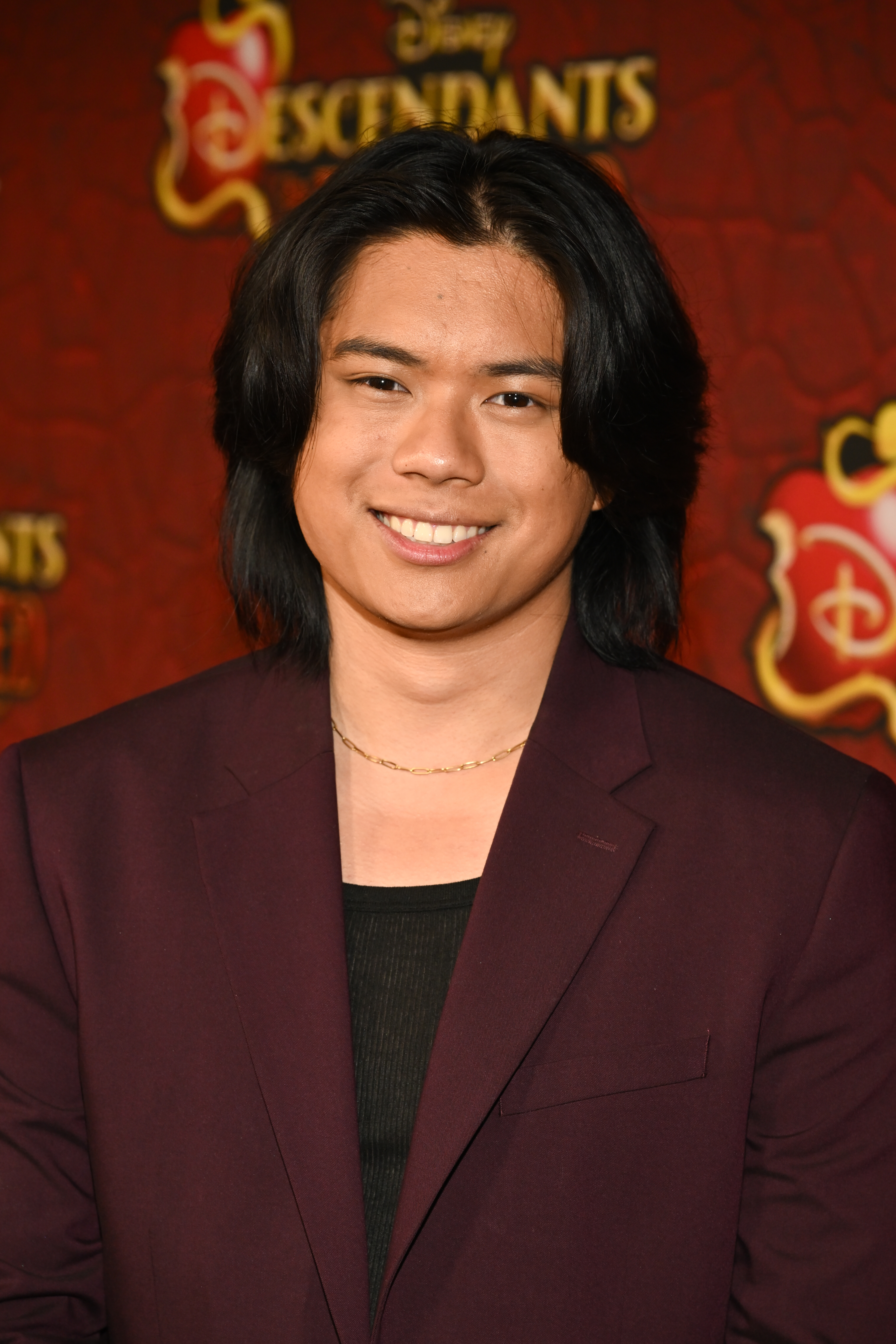 Tristan Padil on the red carpet for "Descendants: The Rise of Red" in a maroon suit